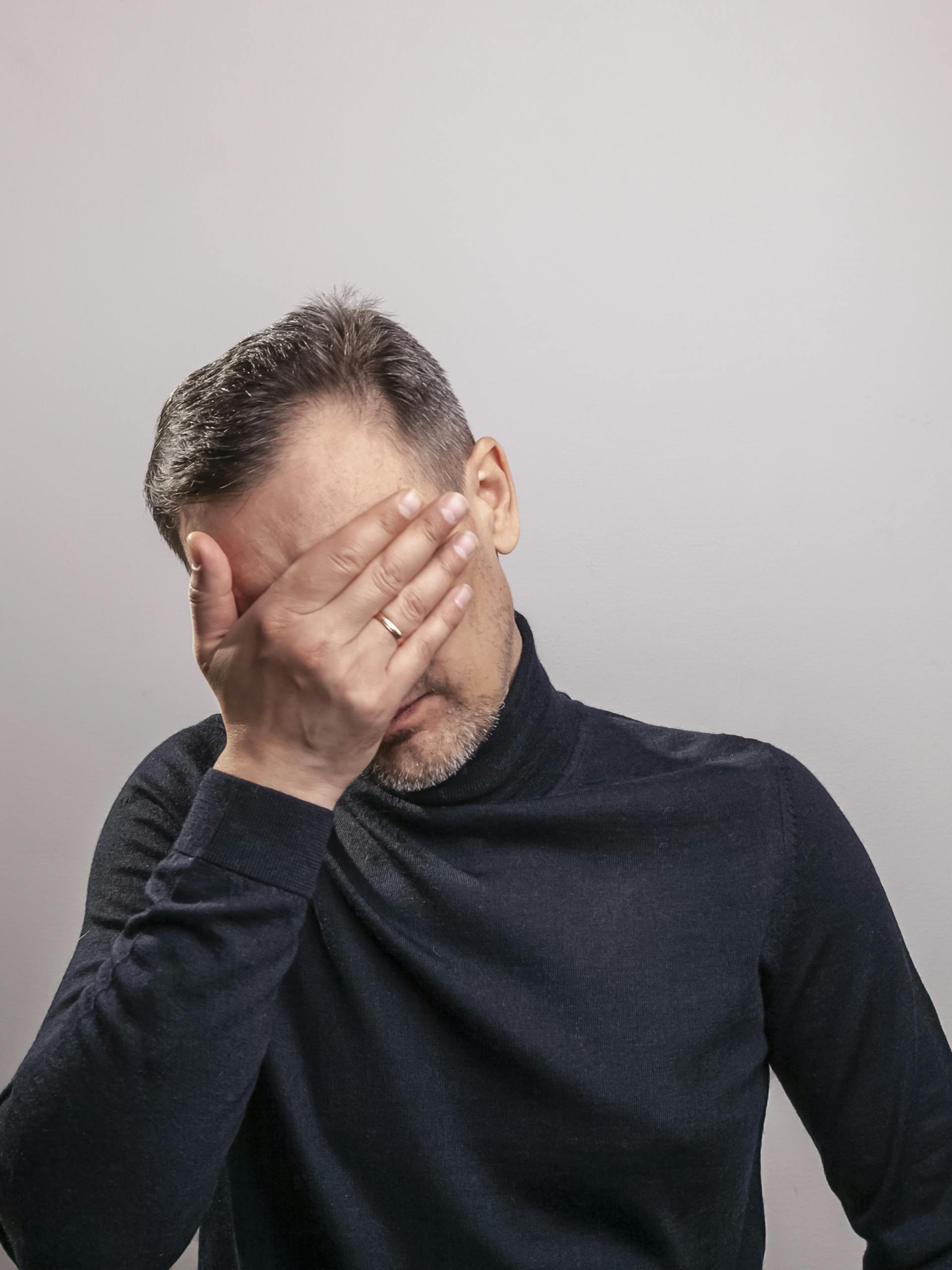 Ein Mann, der sein Gesicht mit seiner Hand bedeckt | Quelle: Pexels