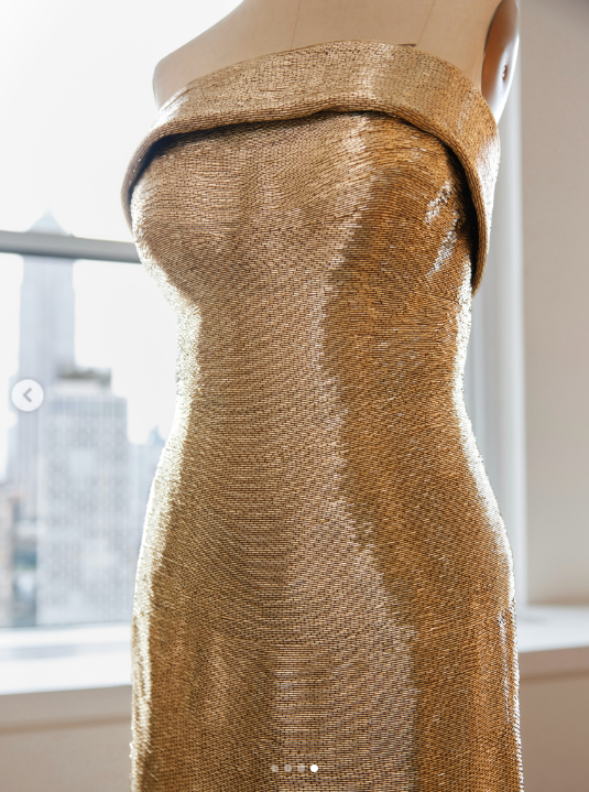 Das goldene Kleid mit Bugle-Perlen von Oscar de la Renta für Usha Vance wird an einer Schaufensterpuppe präsentiert und besticht durch seine trägerlose Silhouette, den kunstvoll geformten Ausschnitt und den reich verzierten, schmalen Schnitt. | Quelle: Instagram/oscardelarenta