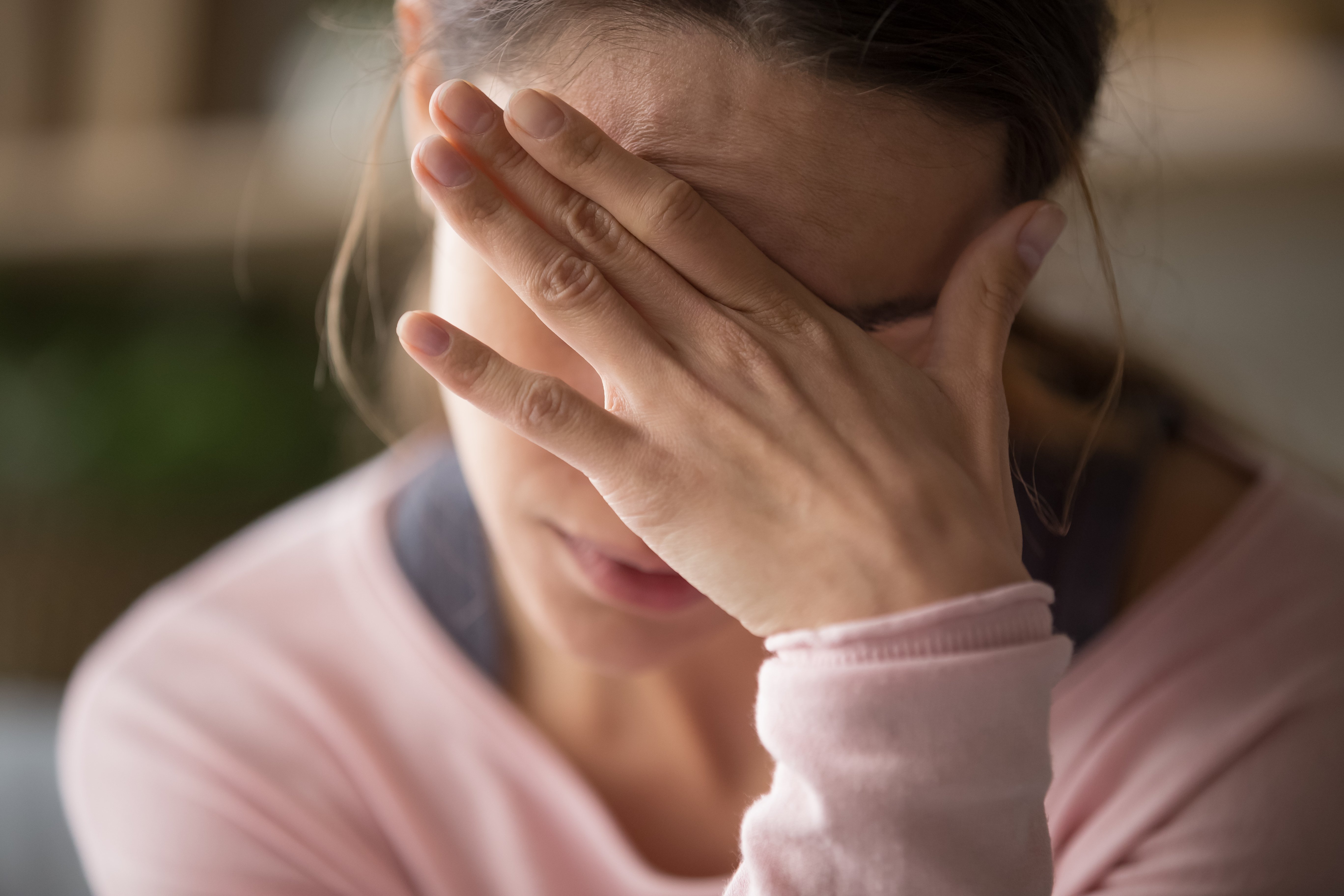 Traurige müde junge Frau, die Stirn berührt, die Kopfschmerzen, Migräne oder Depression hat | Quelle: Shutterstock