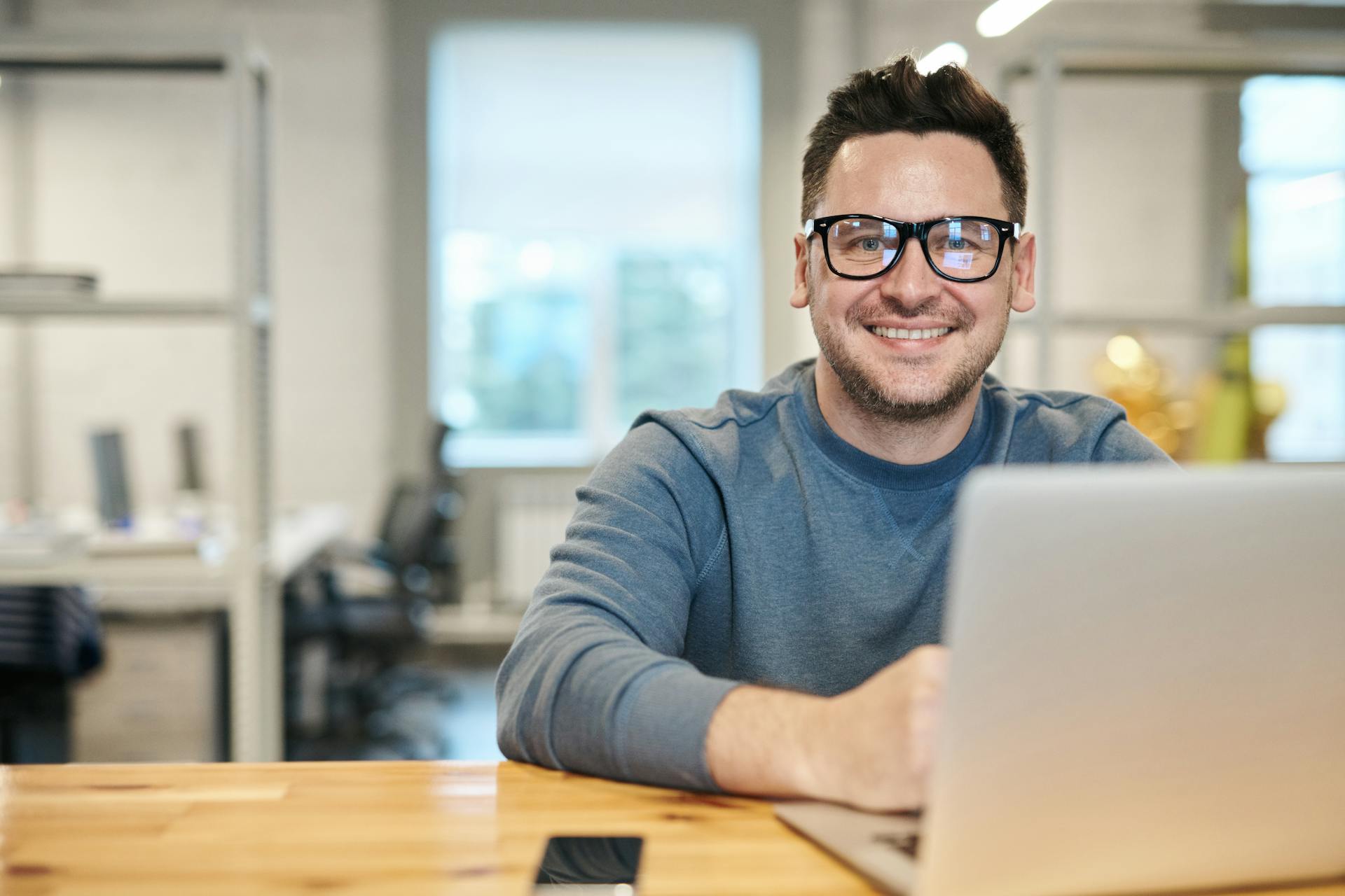 Ein lächelnder Mann benutzt einen Laptop in seinem Büro | Quelle: Pexels