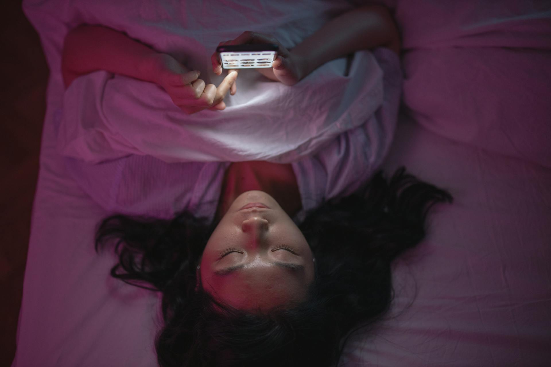 Eine Frau, die im Bett auf ihr Telefon schaut | Quelle: Pexels