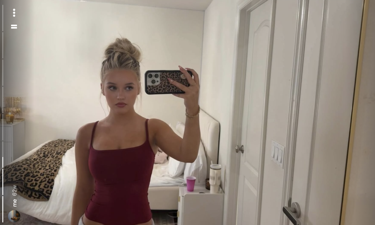 Finley Lockwood macht in ihrem Schlafzimmer ein lässiges Spiegel-Selfie – sie trägt ein tief weinrotes Top mit quadratischem Ausschnitt und hat ihr blondes Haar zu einem hohen, zerzausten Dutt hochgesteckt. | Quelle: Instagram/finleyl.ockwood