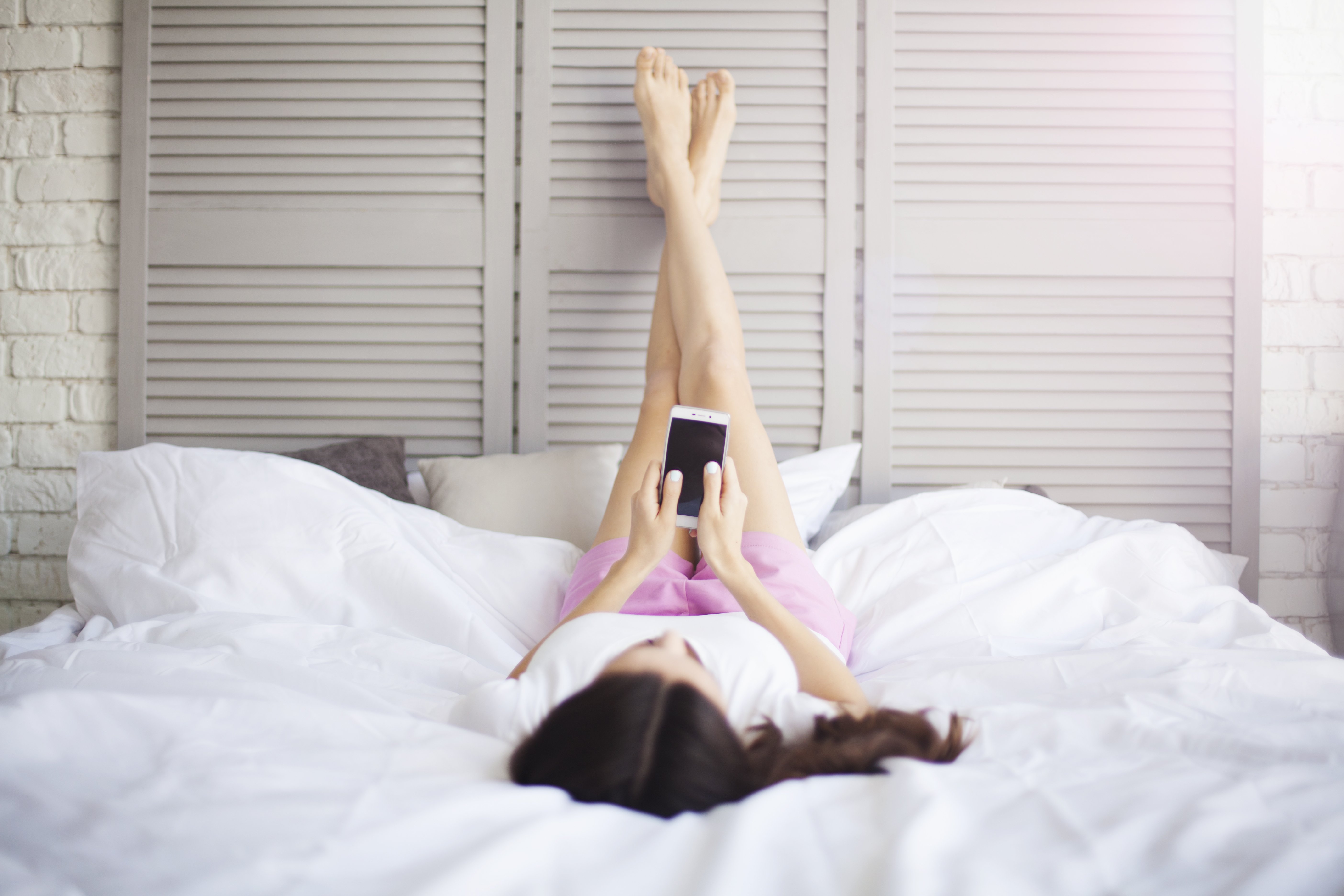 Frau liegt auf Bett mit Beinen hoch | Quelle: Shutterstock