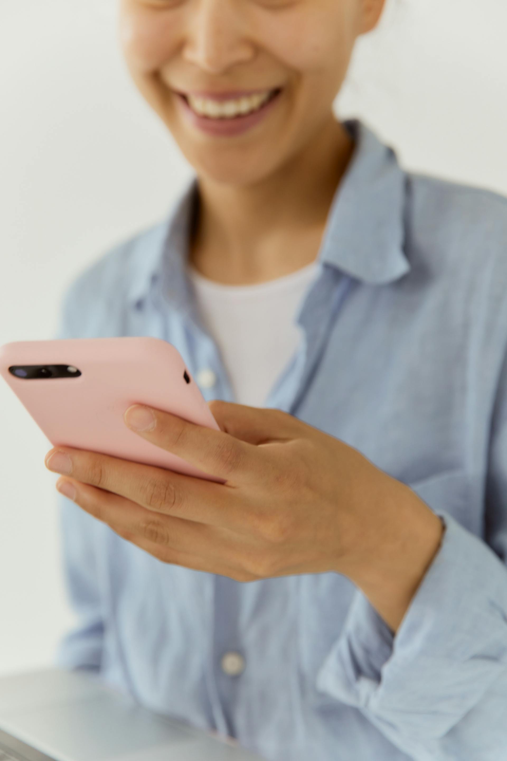 Eine Frau lächelt, während sie auf ihr Telefon schaut | Quelle: Pexels