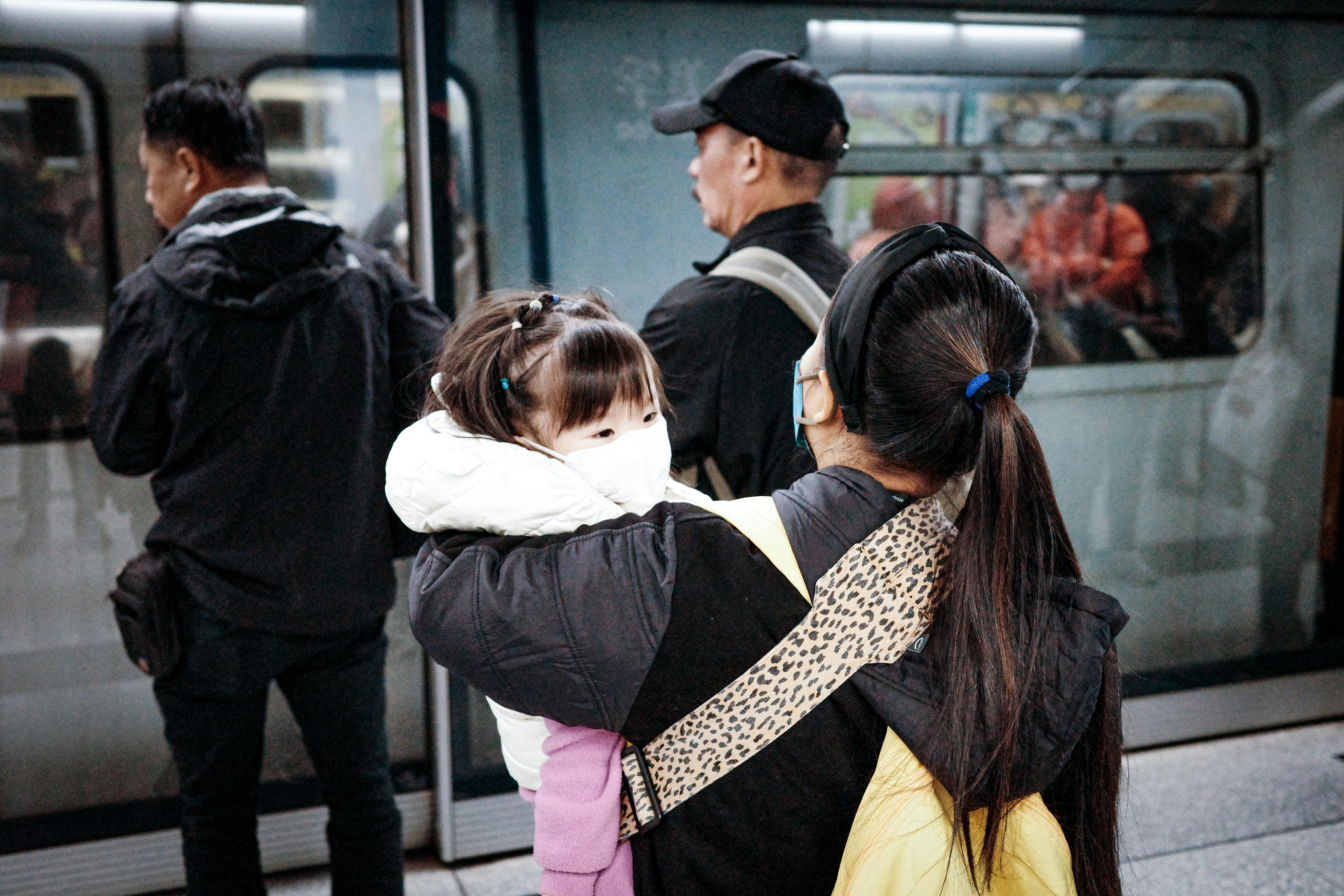 Eine Frau hält ein Kind, das in die U-Bahn einsteigen will | Quelle: Pexels