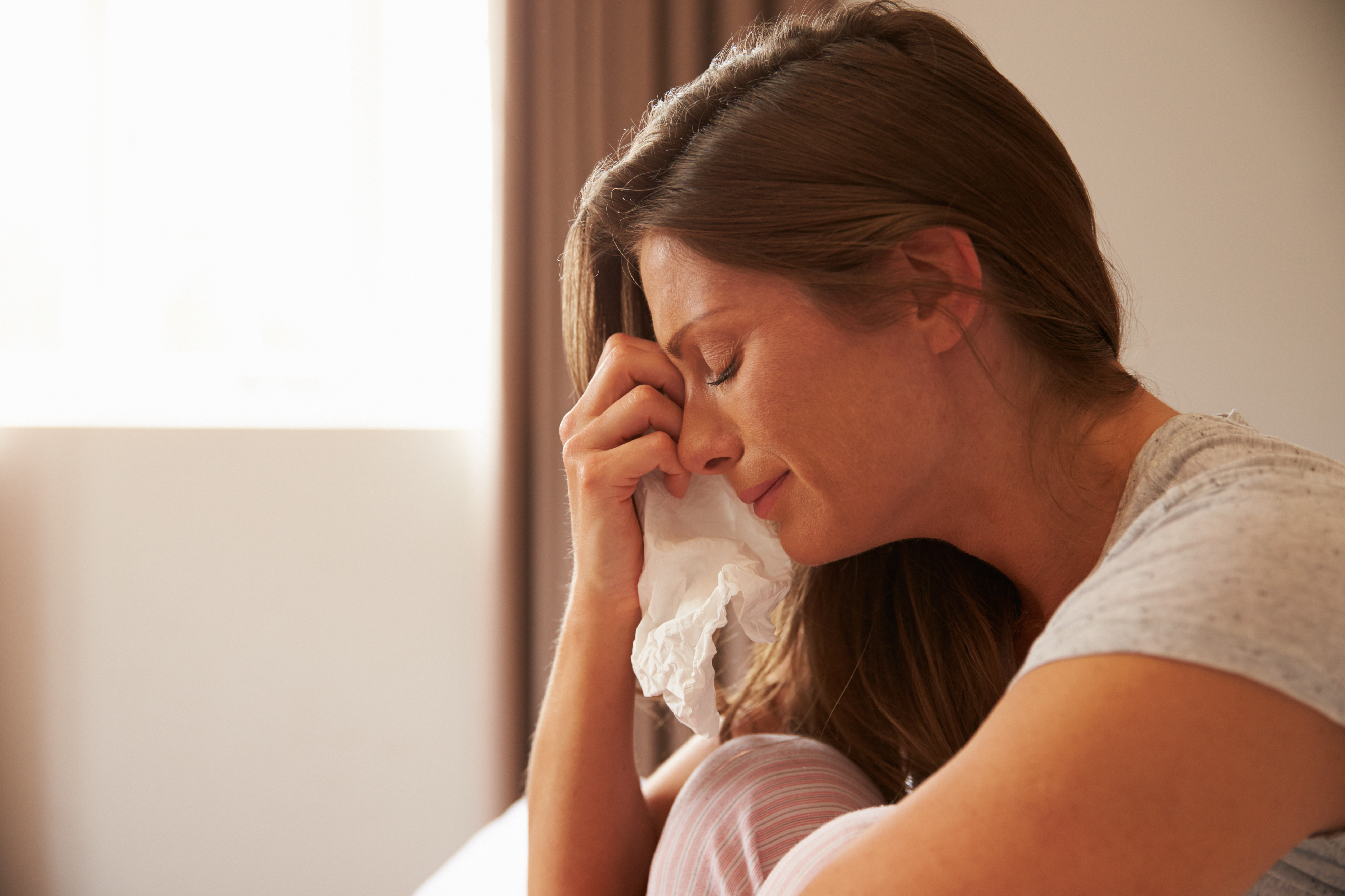 Eine weinende Frau, die ihre Tränen mit einem Taschentuch abwischt | Quelle: Shutterstock
