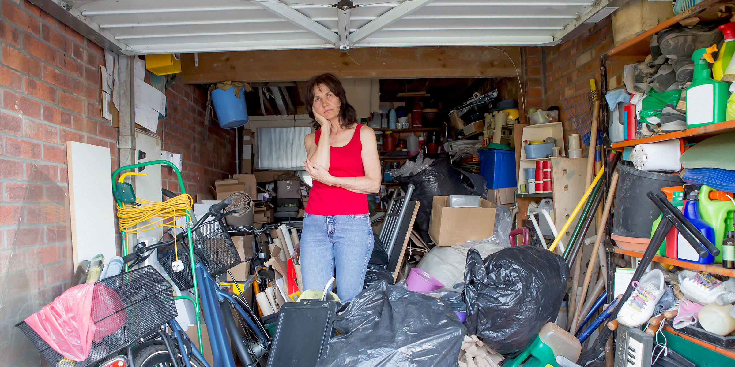 Eine Frau steht in einer Garage, die mit verschiedenen Gegenständen gefüllt ist | Quelle: Shutterstock