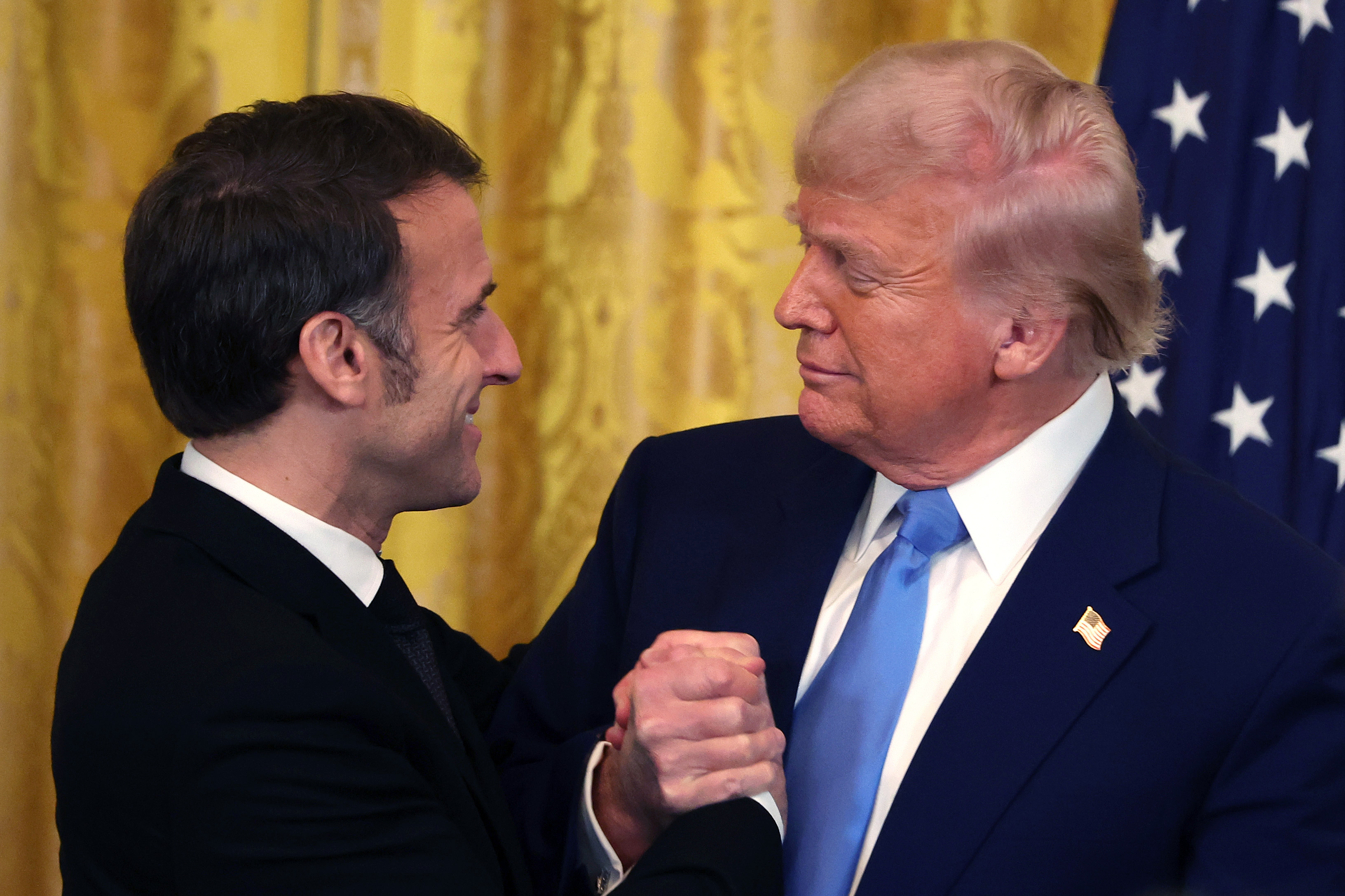 Emmanuel Macron und Donald Trump schütteln sich die Hände und umarmen sich im East Room des Weißen Hauses in Washington, D.C., am 24. Februar 2025. | Quelle: Getty Images