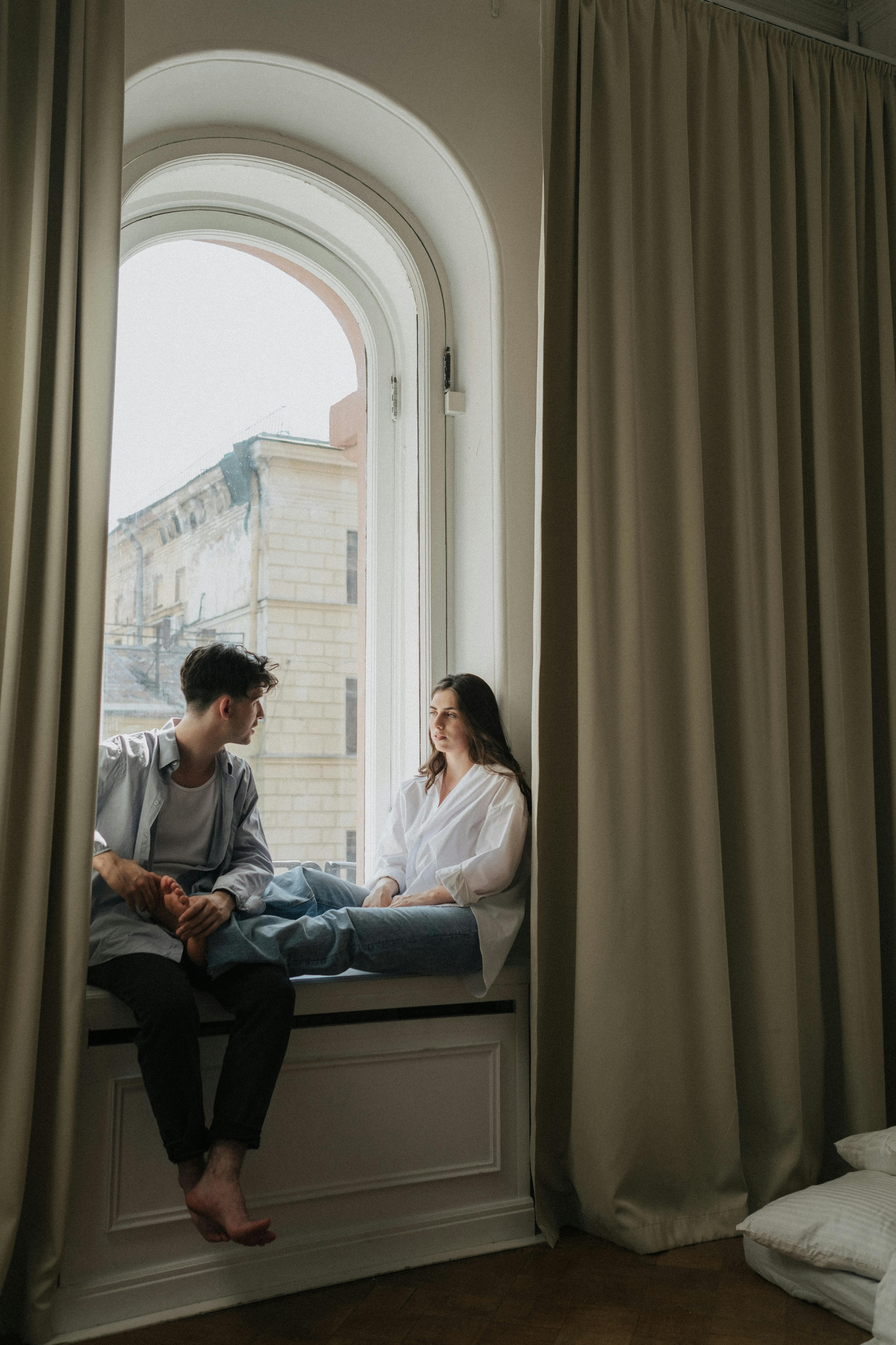 Mann und Frau sitzen am Fenster und unterhalten sich | Quelle: Pexels
