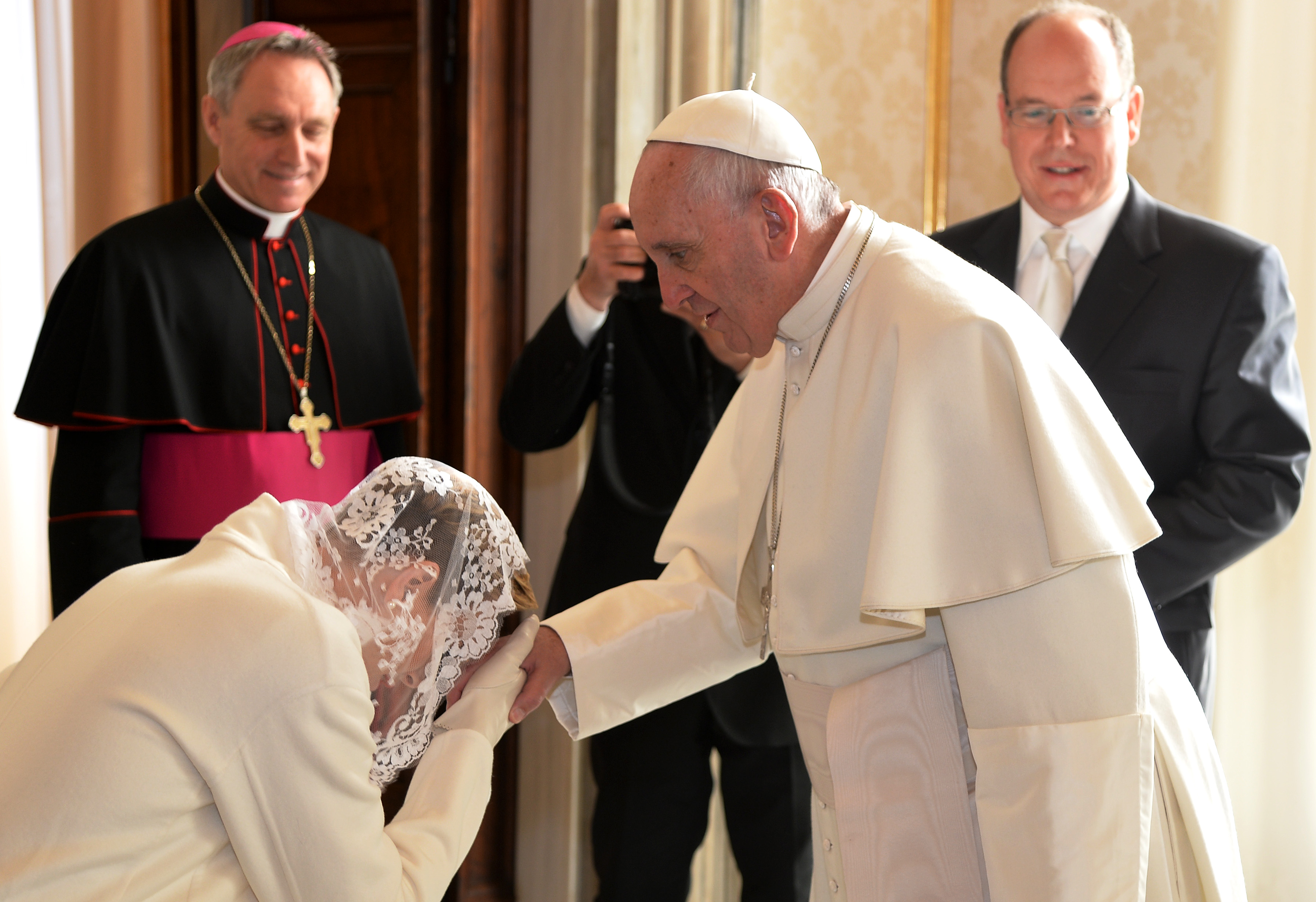 Charlene, Fürstin von Monaco, küsst Papst Franziskus die Hand, während ihr Ehemann, Fürst Albert II. von Monaco, vor einer Privataudienz mit dem Pontifex im Vatikan am 18. Januar 2016 zusieht | Quelle: Getty Images