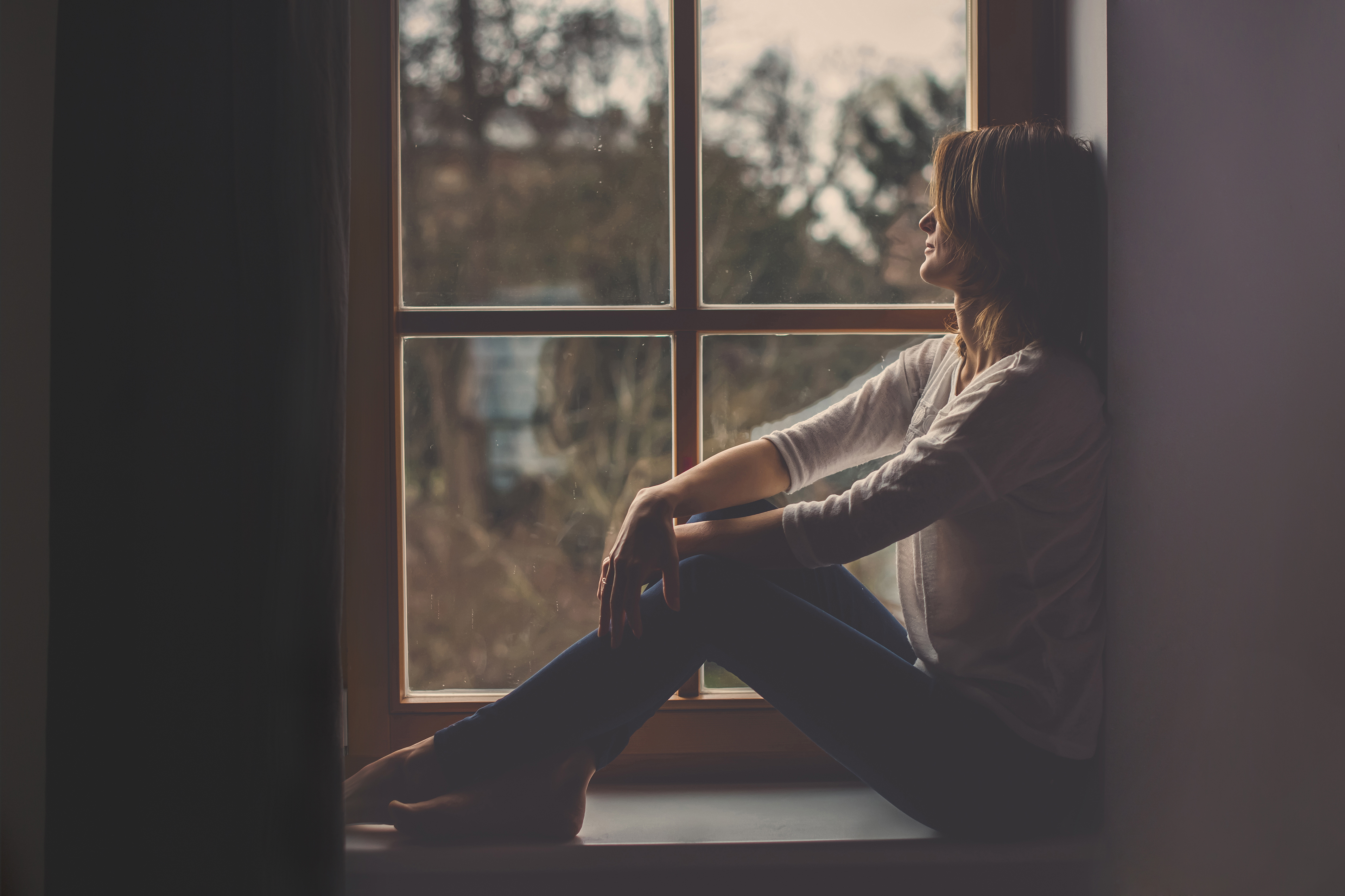 Einsame Frau sitzt am Fenster | Quelle: Shutterstock
