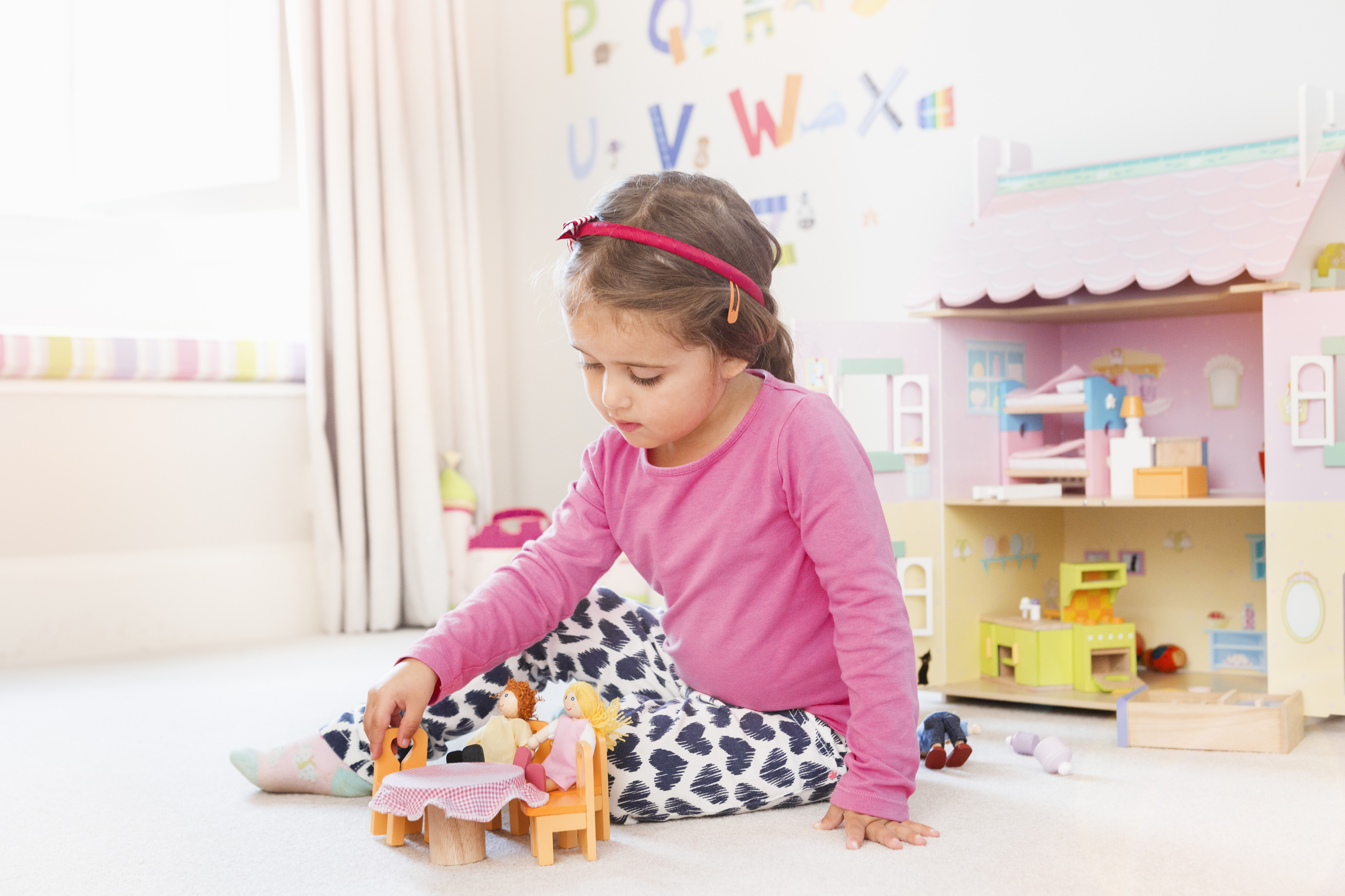 Junges Mädchen spielt mit einem Puppenhaus im Schlafzimmer | Quelle: Getty Images