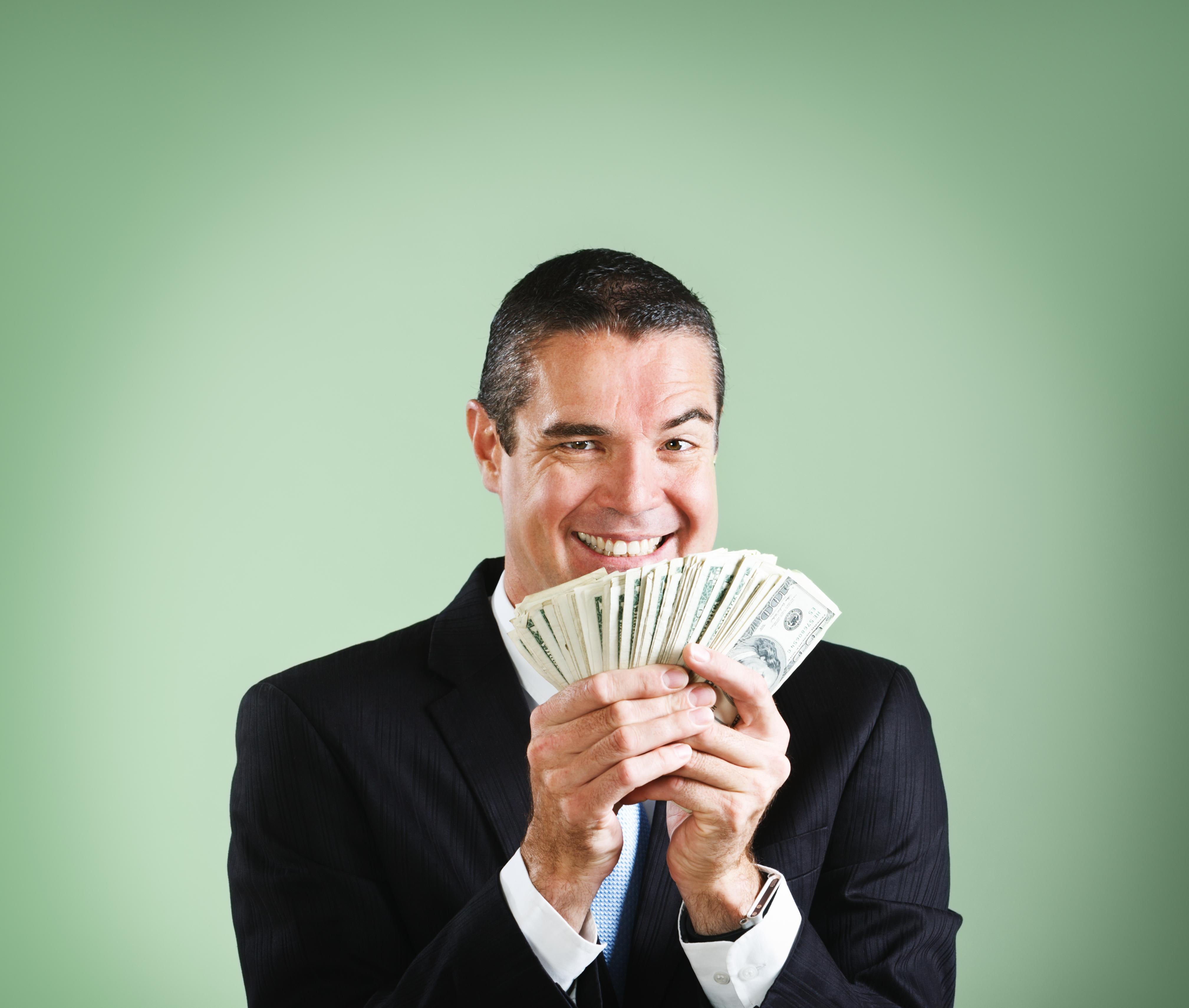 Ein gut gelaunter Geschäftsmann grinst und freut sich über eine Handvoll Dollar | Quelle: Getty Images