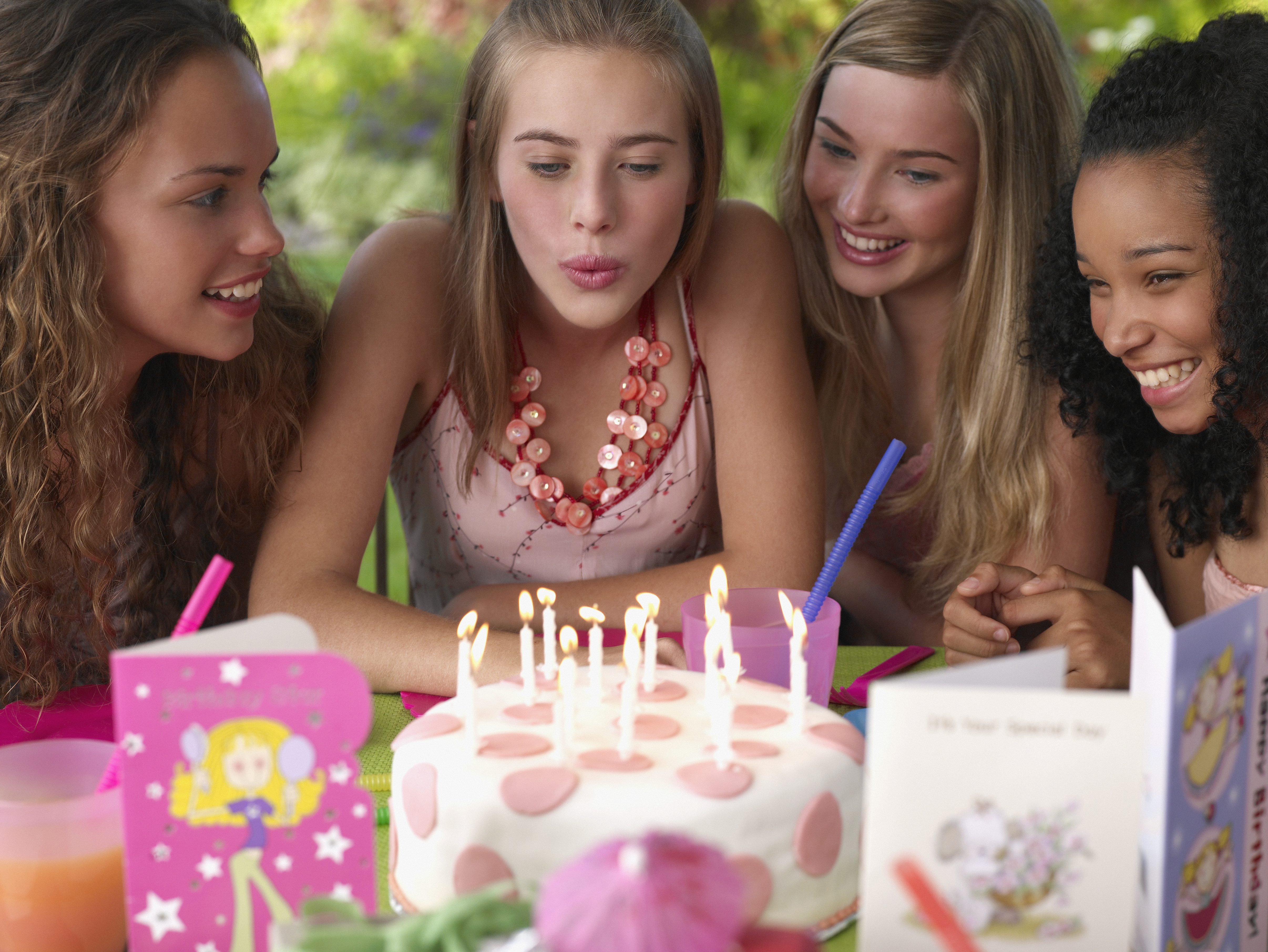 Vier jugendliche Mädchen auf einer Geburtstagsparty lächelnd im Freien | Quelle: Getty Images