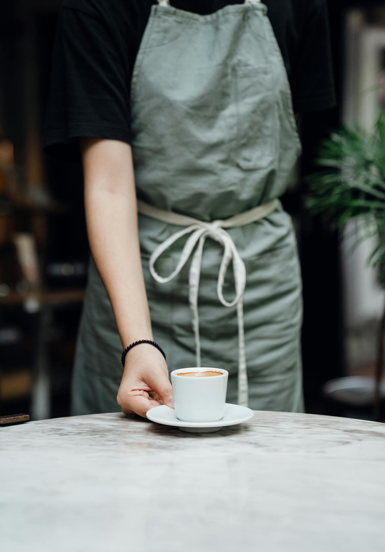 Eine Kellnerin stellt eine Tasse Kaffee auf den Tisch | Quelle: Pexels