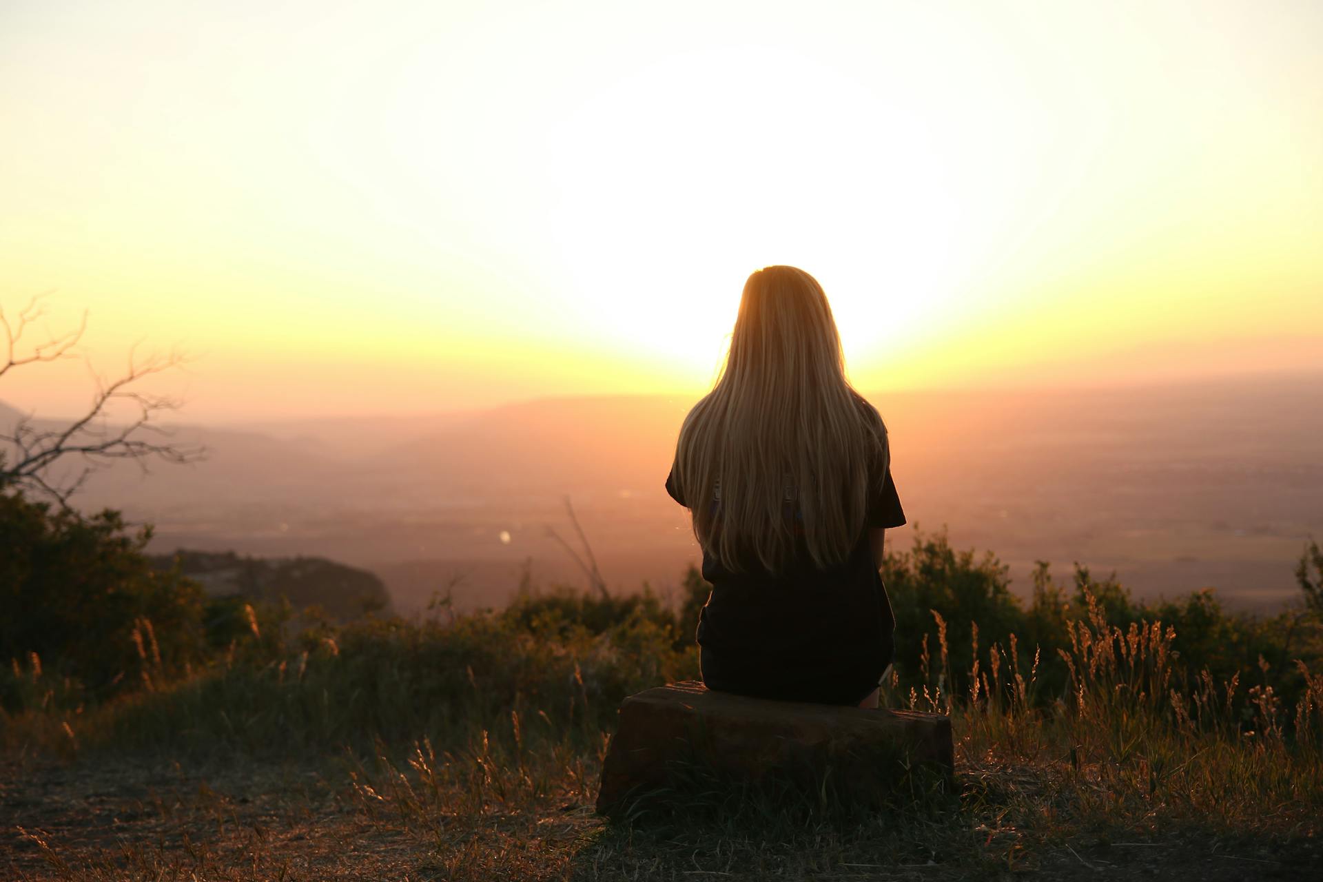 Frau, die auf einem Berg sitzt und die Aussicht genießt | Quelle: Pexels