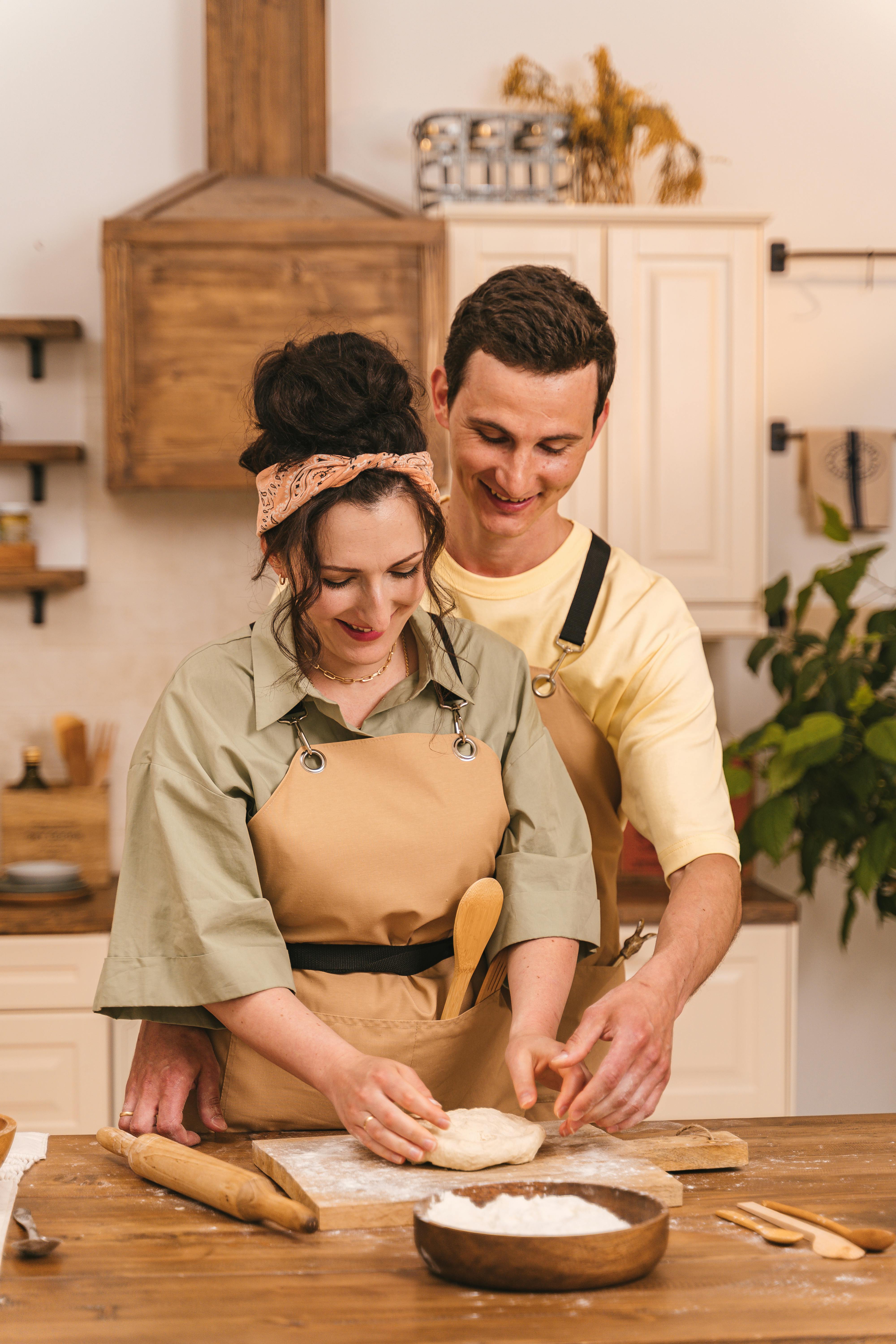 Um homem sorridente observando sua esposa cozinhar | Fonte: Pexels