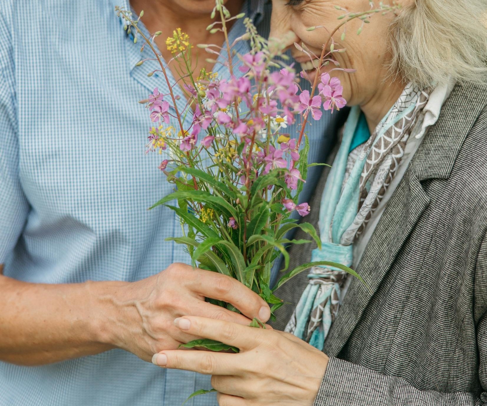 Nahaufnahme eines glücklichen Seniorenpaares mit Blumen in der Hand | Quelle: Pexels