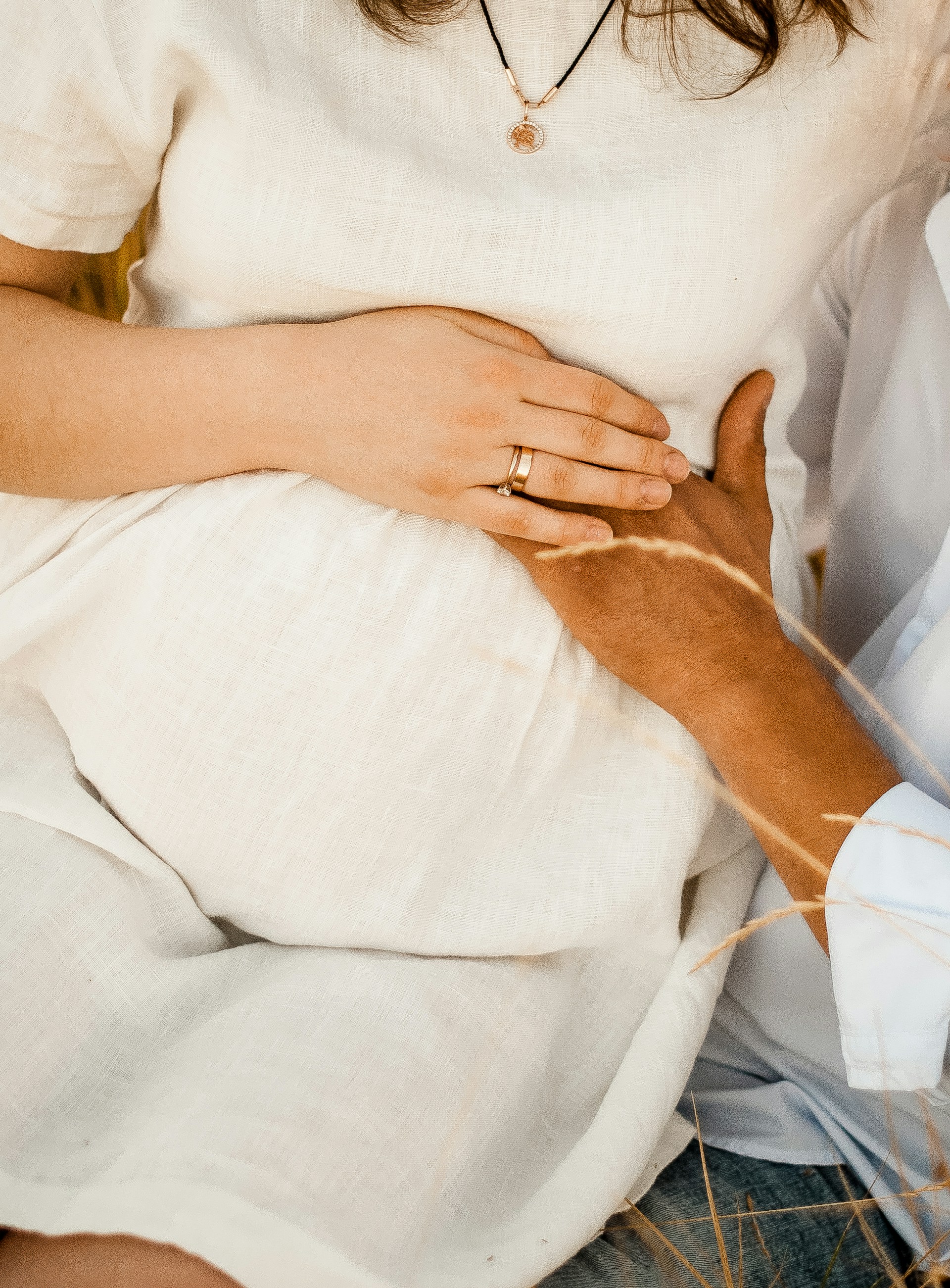 Eine schwangere Frau, die auf dem Schoß eines Mannes sitzt, während er sanft ihren Babybauch berührt | Quelle: Unsplash