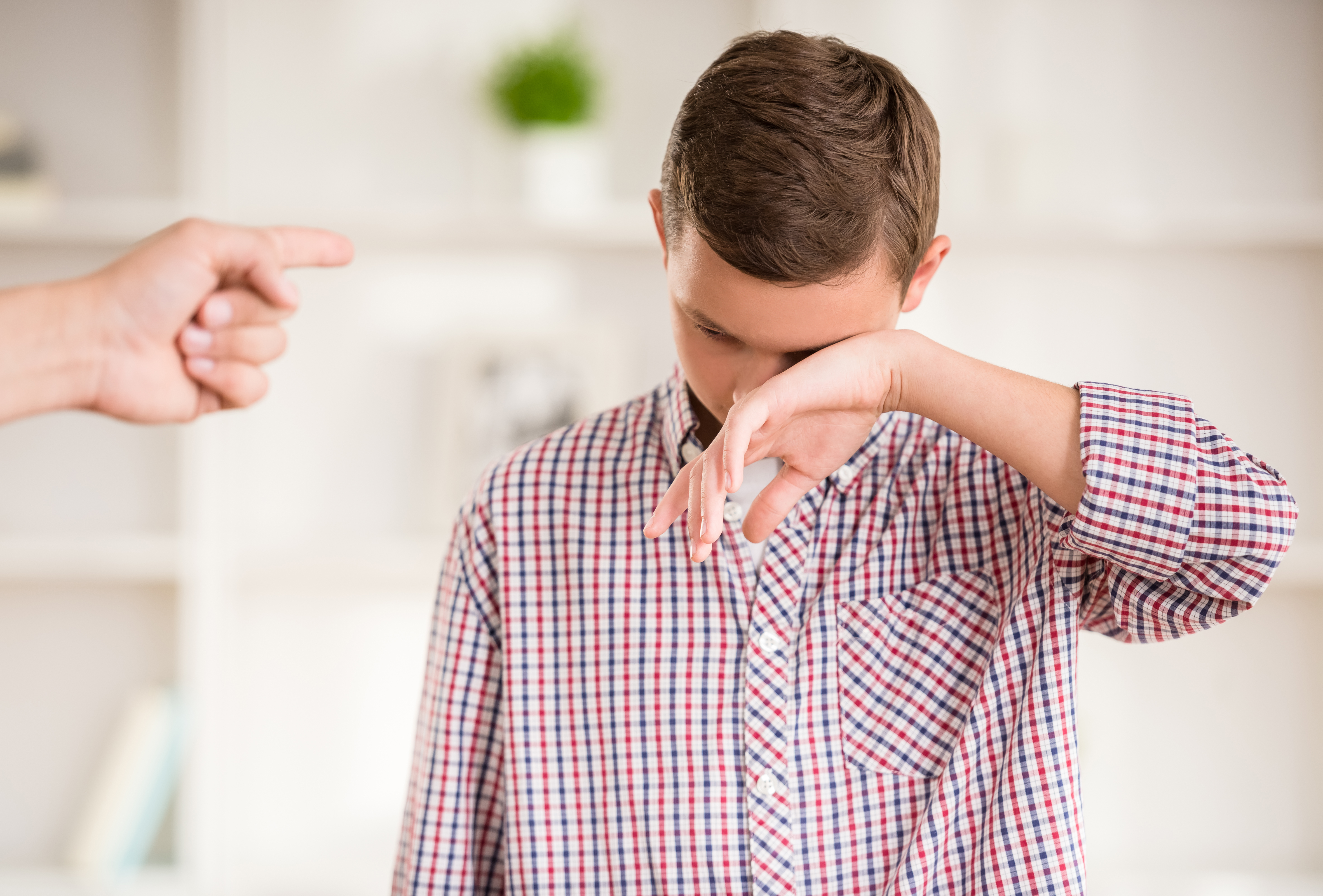 Ein Junge, der zu weinen scheint, während ein Finger auf ihn gerichtet wird | Quelle: Shutterstock