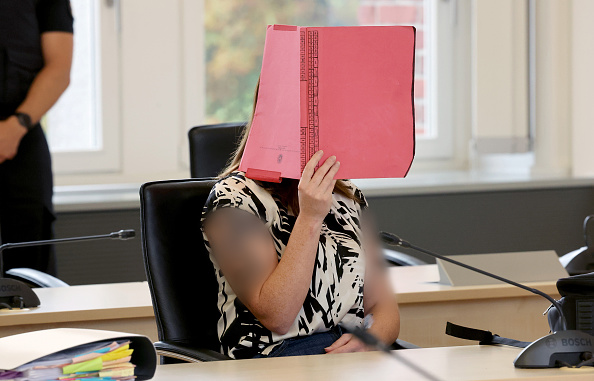 Die Angeklagte sitzt im Gerichtssaal des Landgerichts Rostock und hält eine Aktenmappe vor ihr Gesicht, 7. Juli 2026. | Quelle: Getty Images