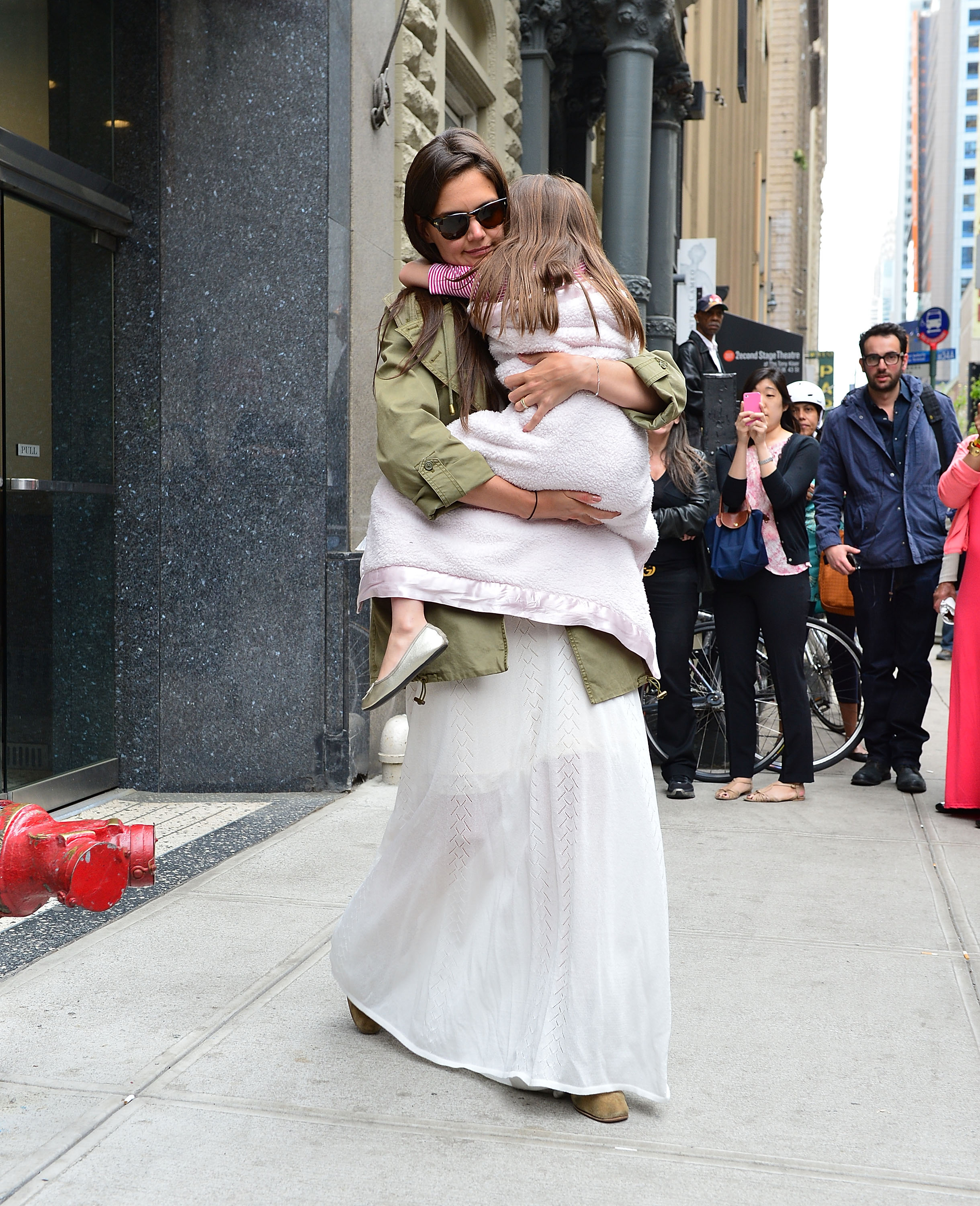 Katie Holmes umarmt ihre Tochter Suri Cruise, als sie am 18. April 2012 durch Manhattan spazieren gehen | Quelle: Getty Images