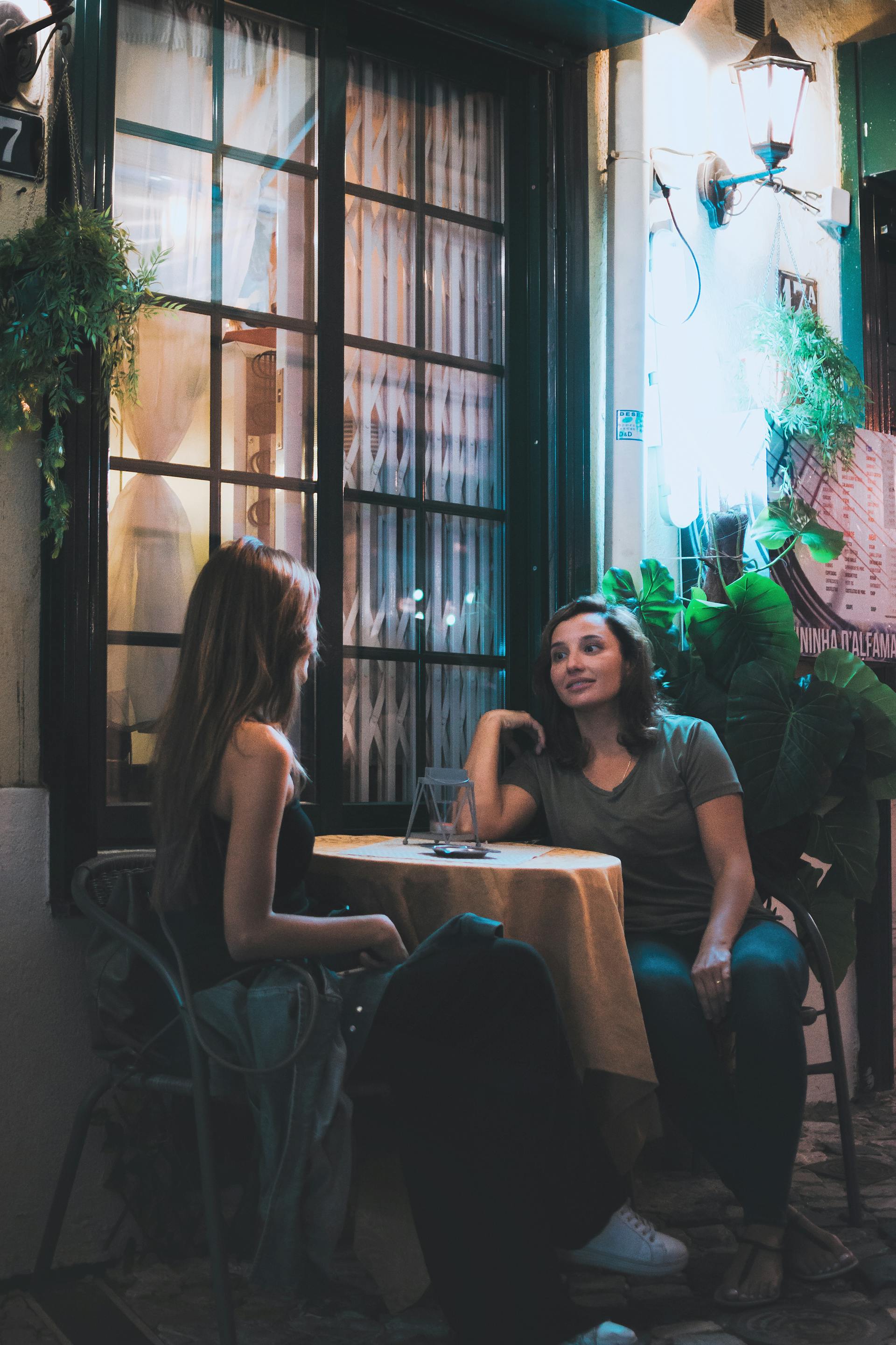 Zwei Frauen unterhalten sich in einem Straßencafé | Quelle: Pexels