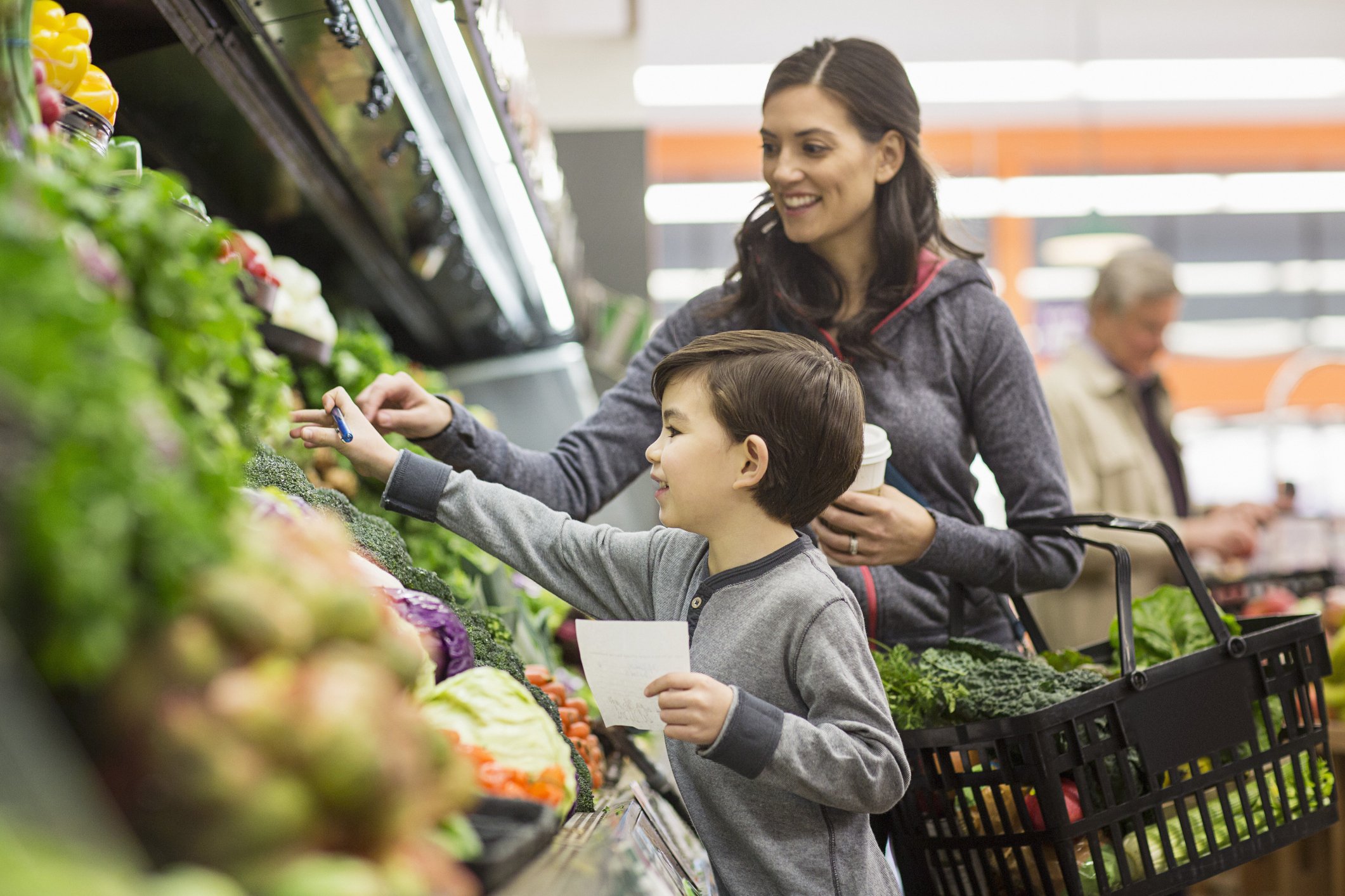 Mutter und Sohn kaufen Gemüse im Supermarkt ein | Quelle: Getty Images