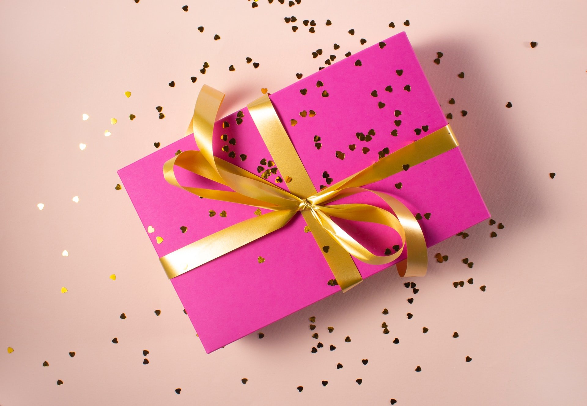 Geschenk in rosa Laken mit goldener Schleife verpackt | Quelle: Unsplash