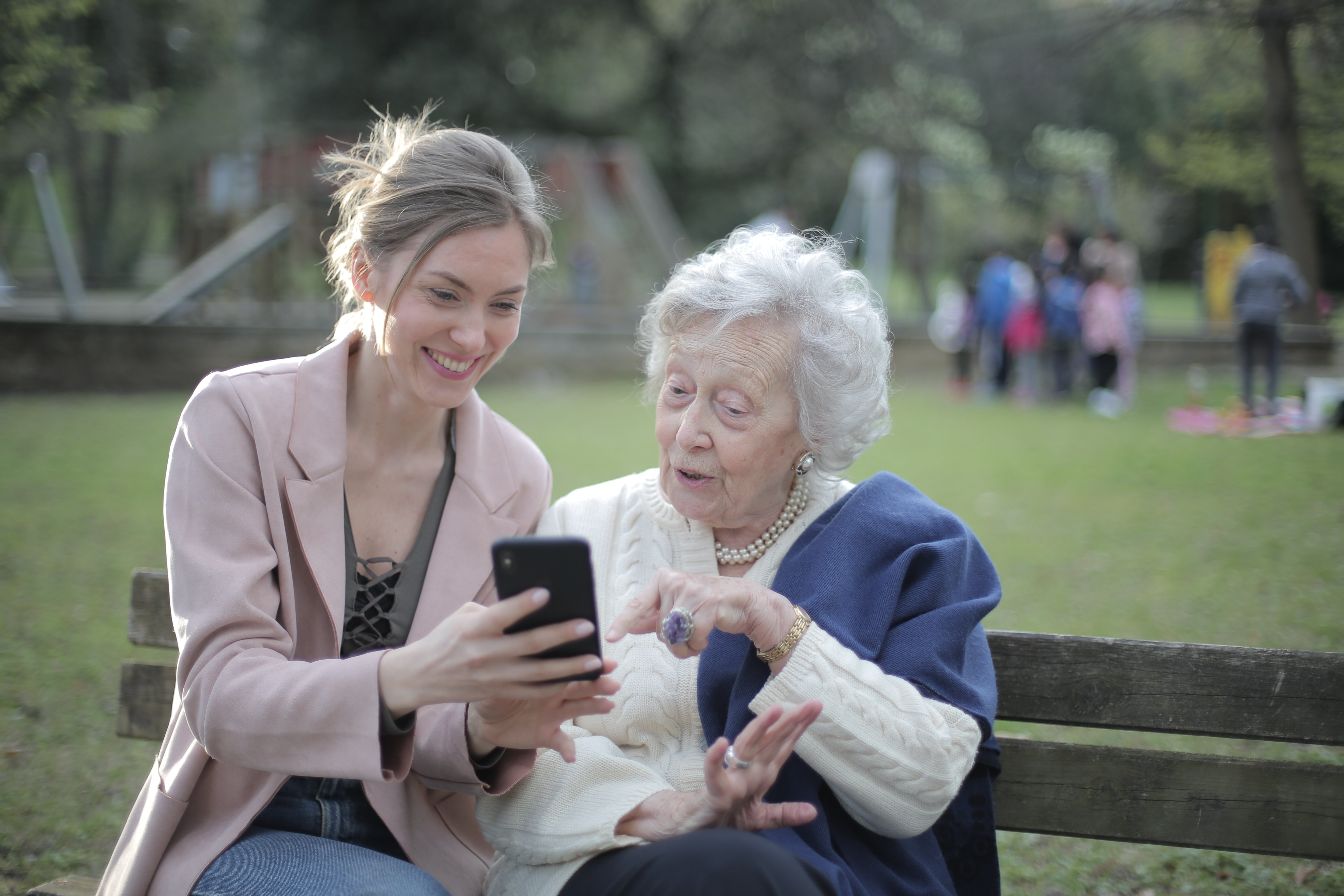Eine ältere Frau sitzt mit einer jungen Dame, die ein Telefon in der Hand hält. | Quelle: Pexels