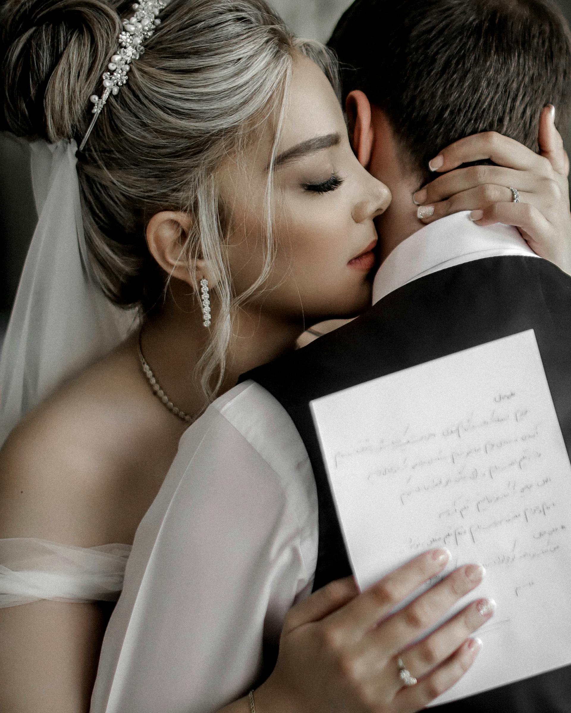 Eine Braut, die ihren Bräutigam umarmt, während sie ein Stück Papier hält | Quelle: Pexels
