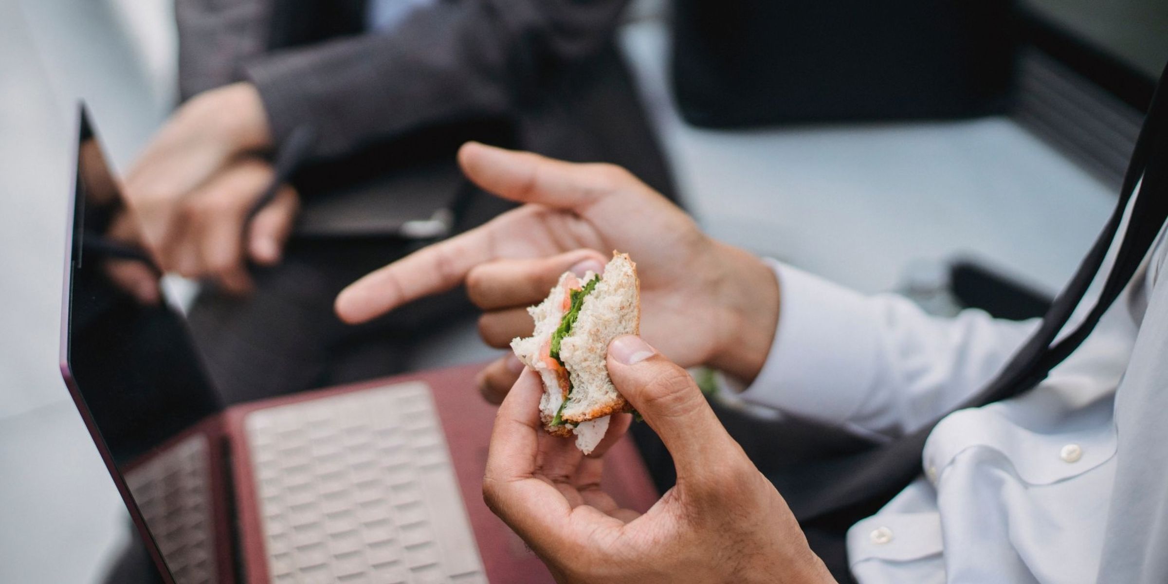 Ein Mann, der ein Sandwich isst, während er am Laptop arbeitet | Quelle: Pexels