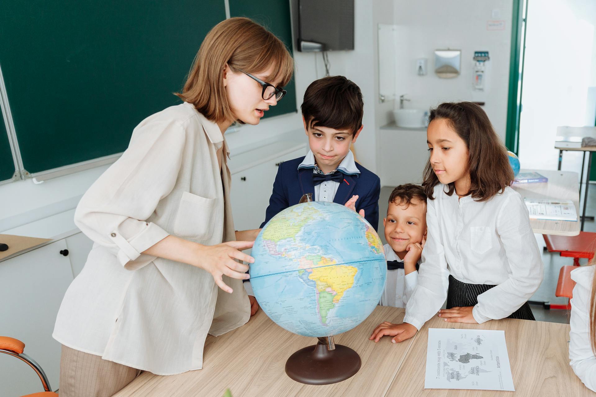 Eine Geografielehrerin mit Schülern in einem Klassenzimmer | Quelle: Pexels