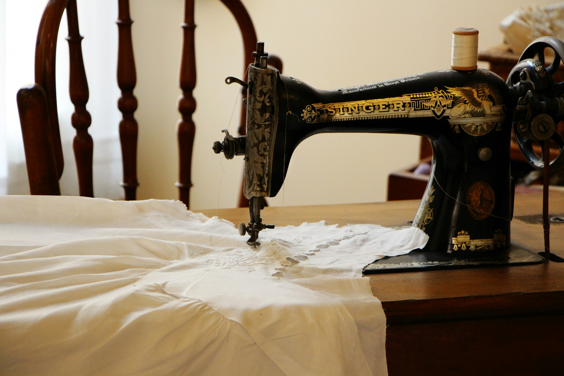 Ein weißes Kleidungsstück wird mit einer Nähmaschine genäht | Quelle: Unsplash