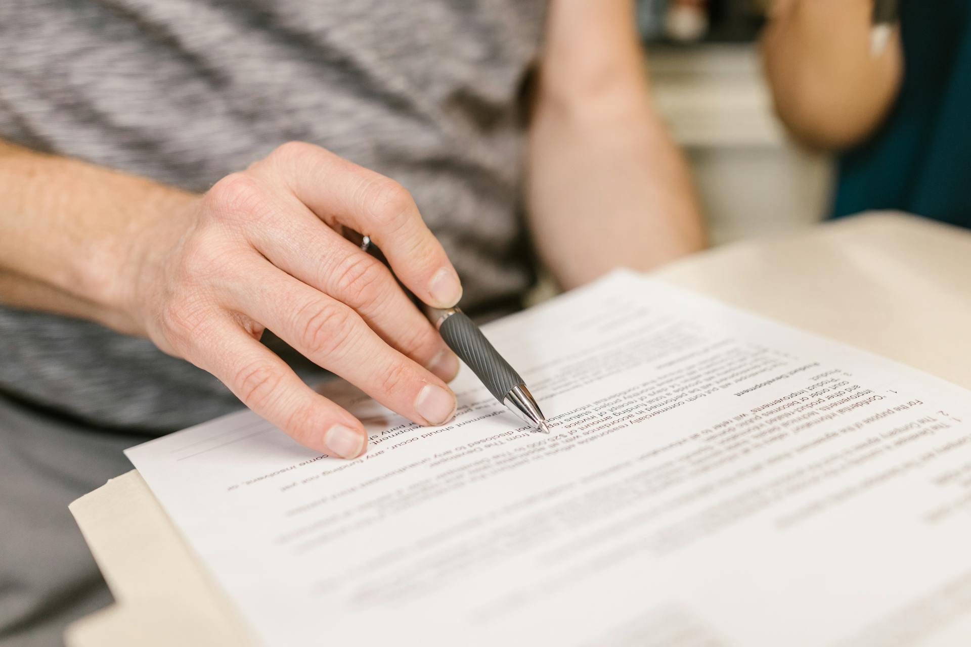 Person hält einen Stift über juristische Dokumente | Quelle: Pexels