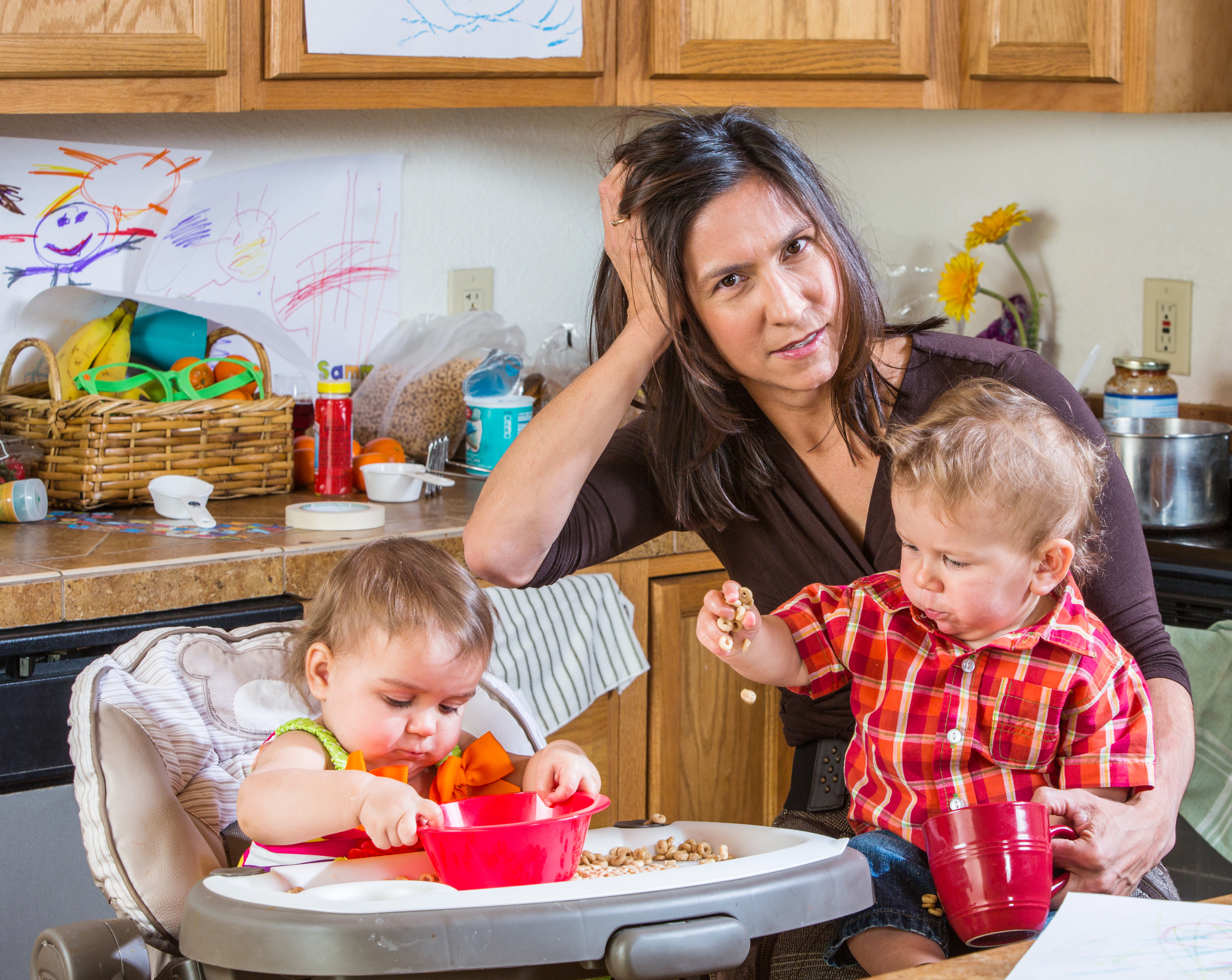 Eine gestresste Mutter in der Küche mit ihren Babys | Quelle: Shutterstock
