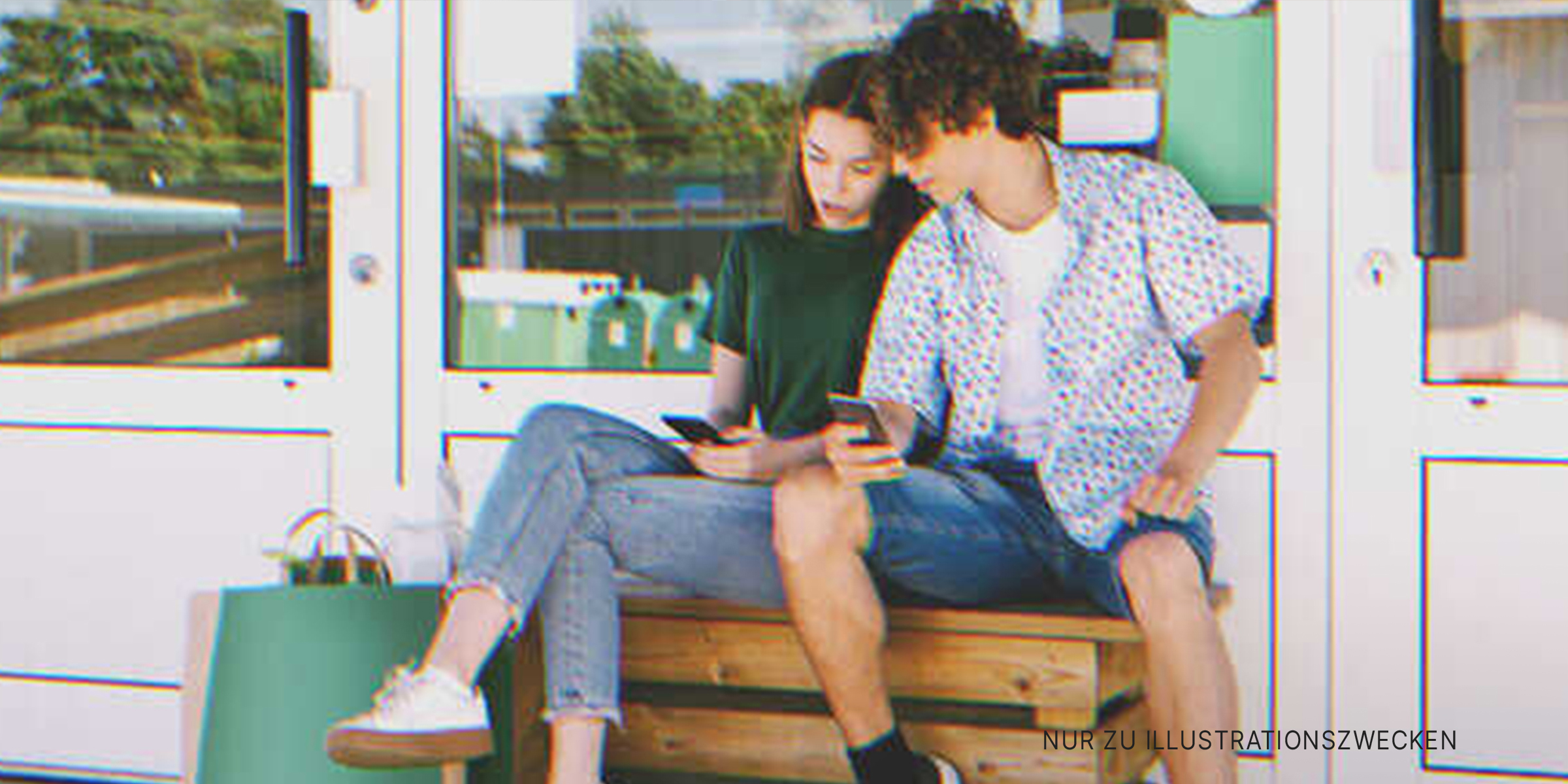 Ein Junge und ein Mädchen sitzen im Freien und schauen auf einen Telefonbildschirm | Quelle: Shutterstock