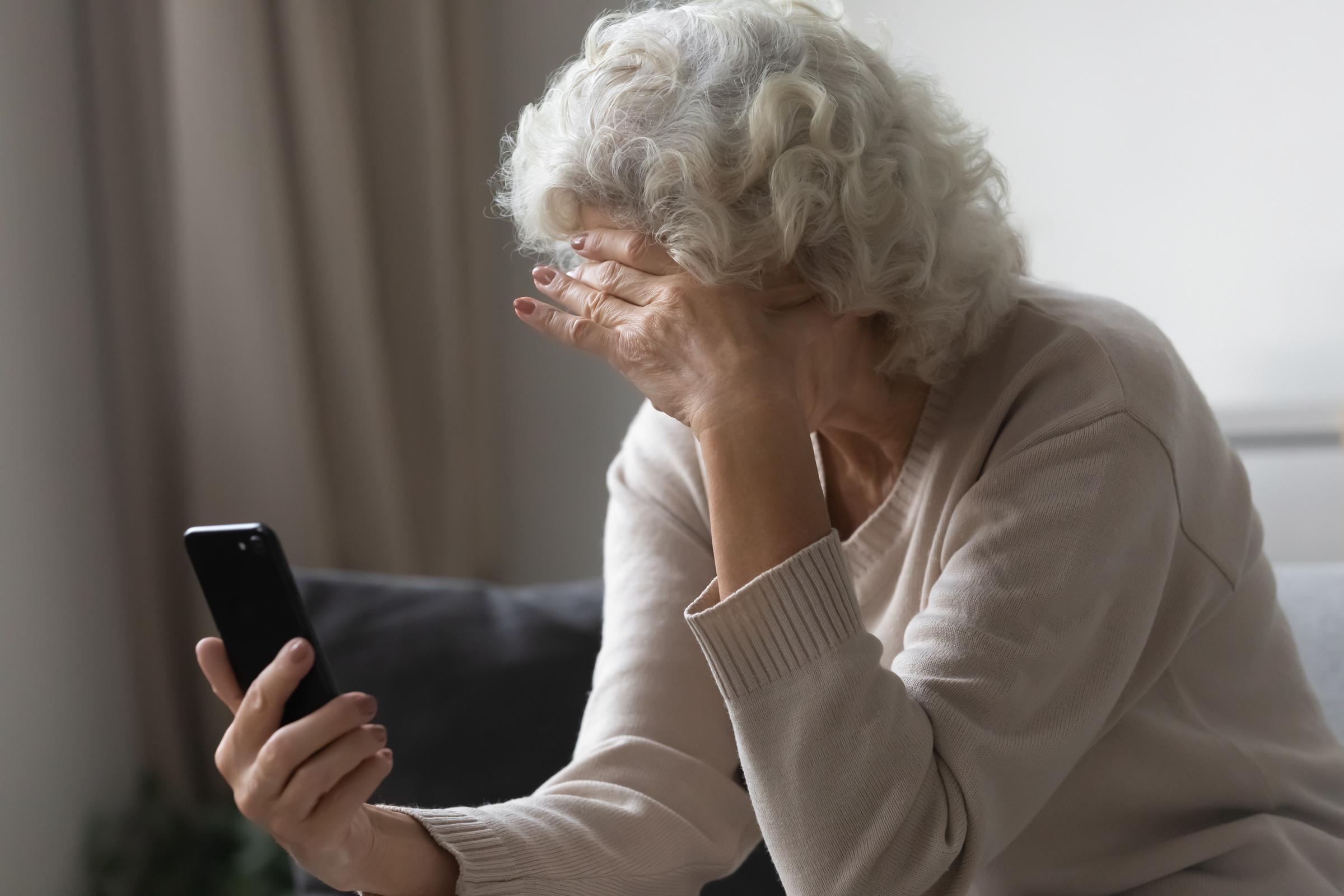 Gestresste ältere Frau schaut auf ihr Telefon | Quelle: Shutterstock