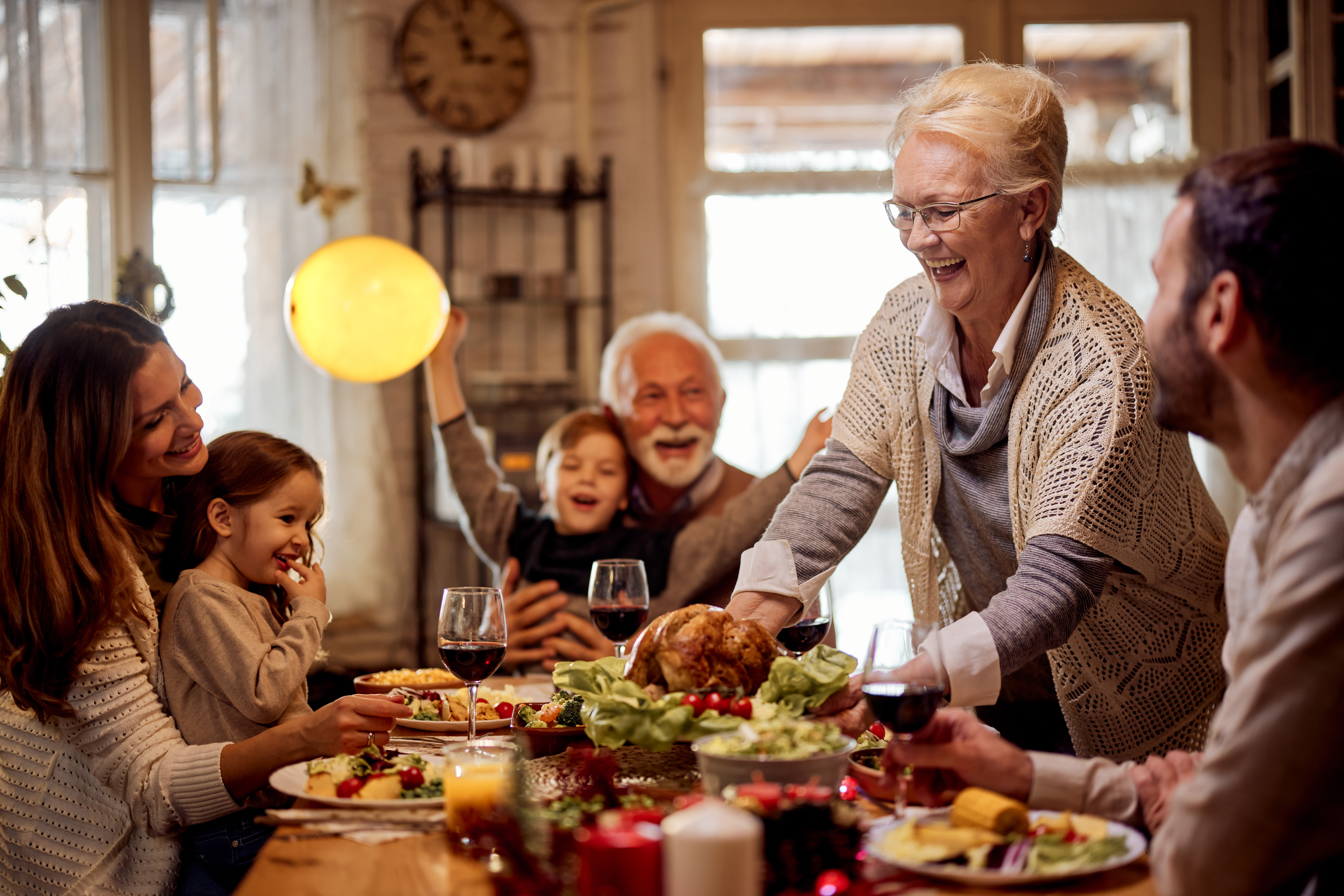 Glückliche ältere Frau, die ihrer Familie im Esszimmer eine Mahlzeit serviert | Quelle: Getty Images
