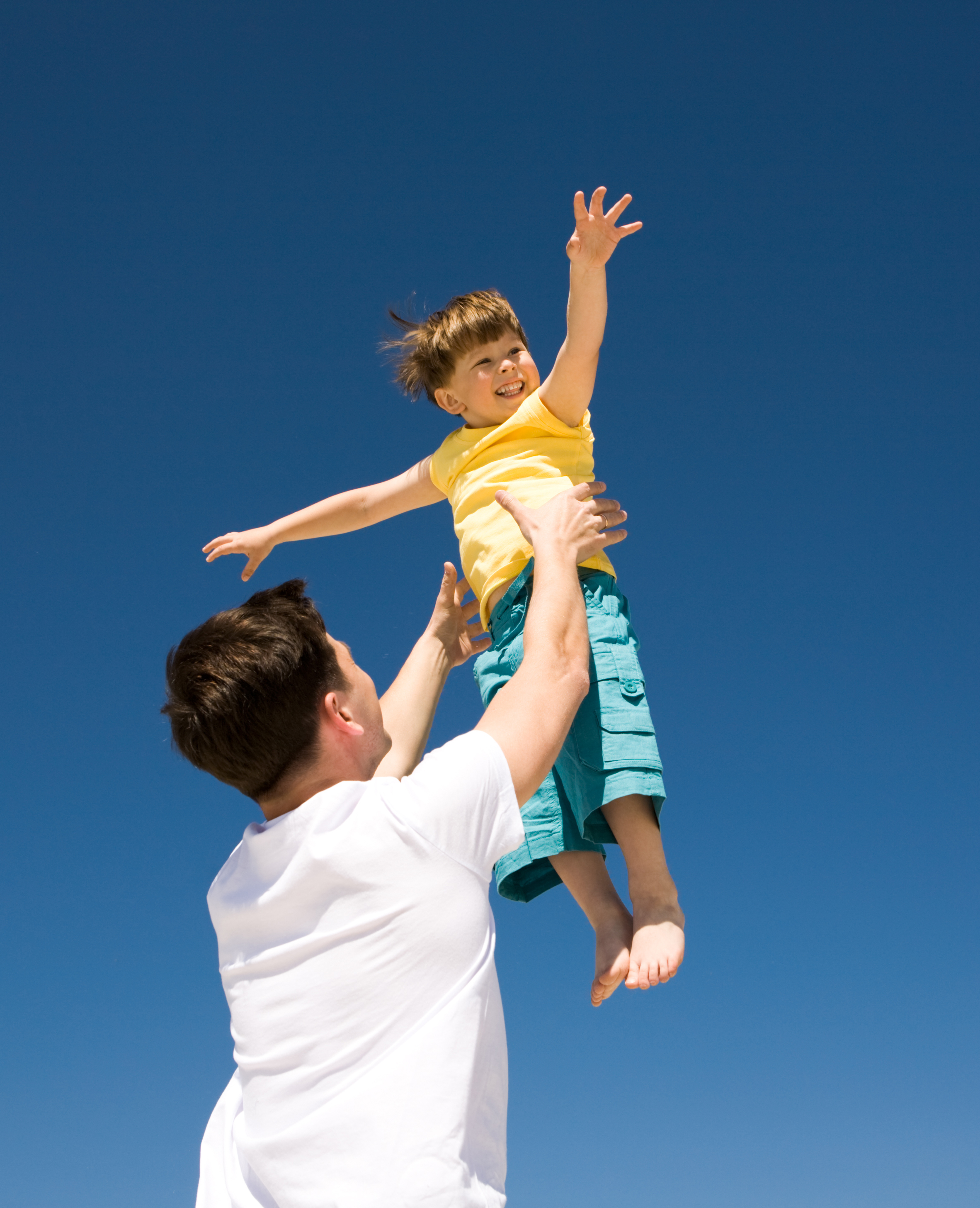 Ein Mann spielt mit einem kleinen Jungen im Freien | Quelle: Shutterstock