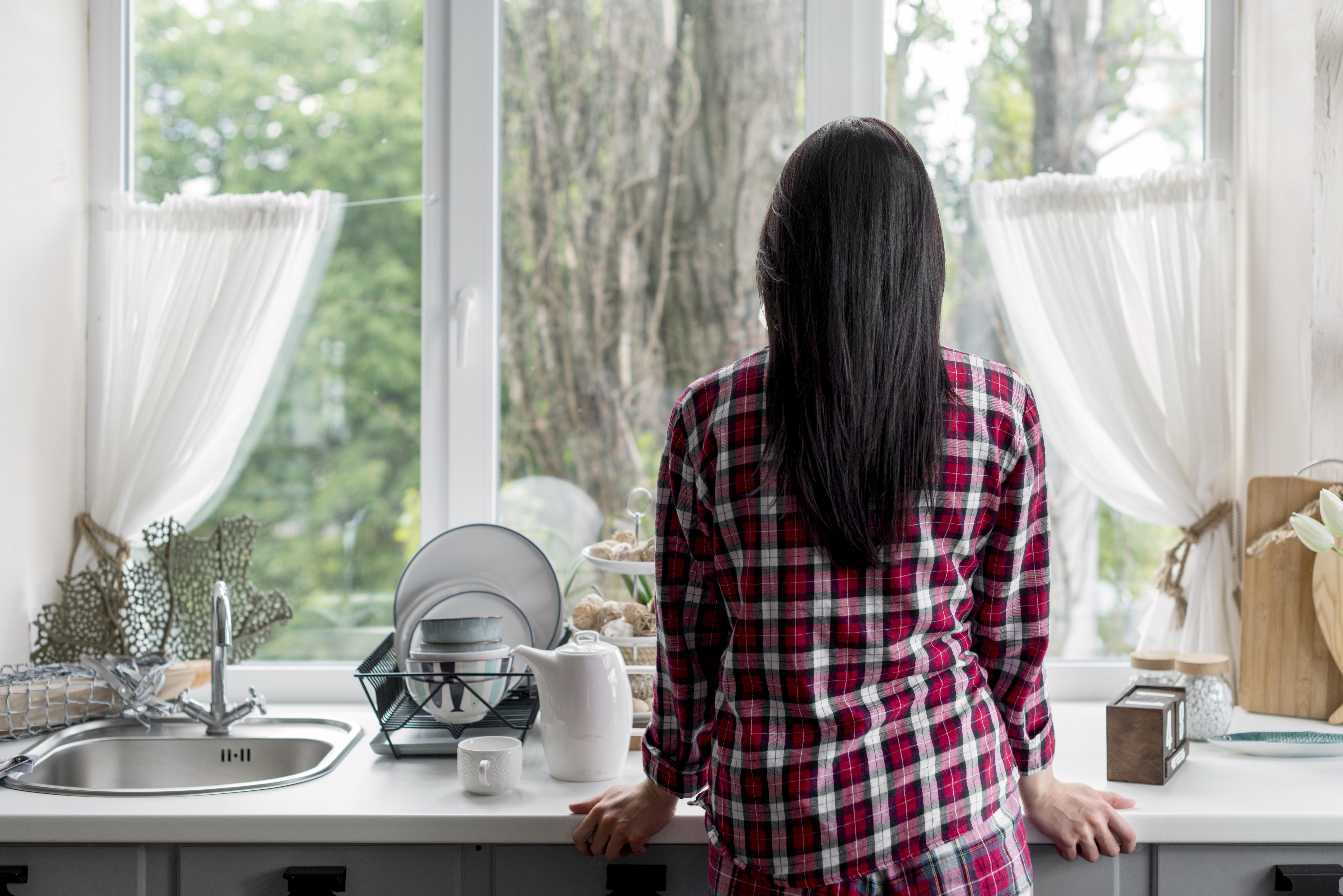 Rückansicht einer Frau, die aus dem Küchenfenster schaut | Quelle: Freepik