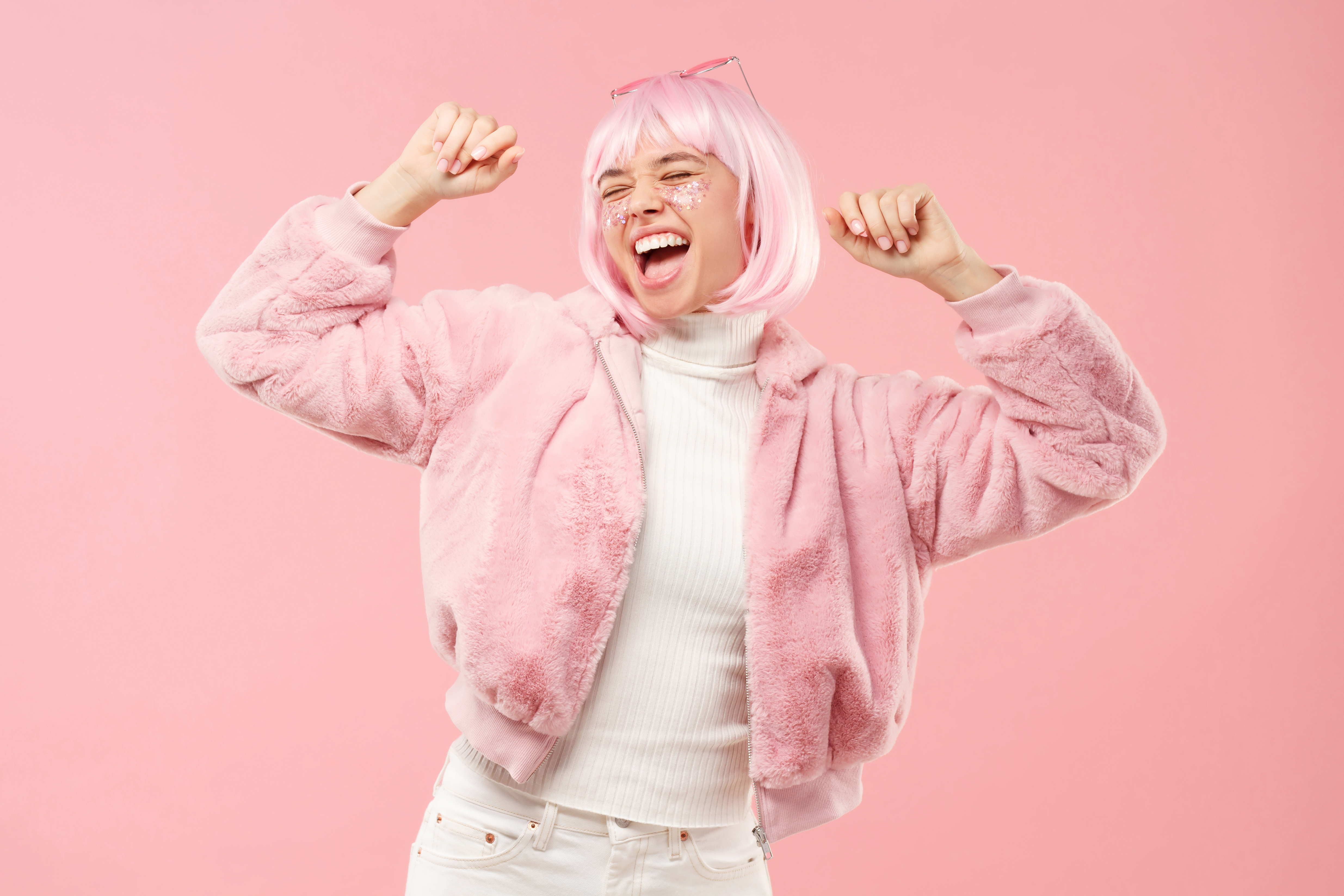 Aufgeregtes jugendliches Mädchen, das zu Musik tanzt und jubelt, mit flauschigem Pelzmantel und bunten Haaren auf einer Party, isoliert auf rosa Hintergrund | Quelle: Getty Images