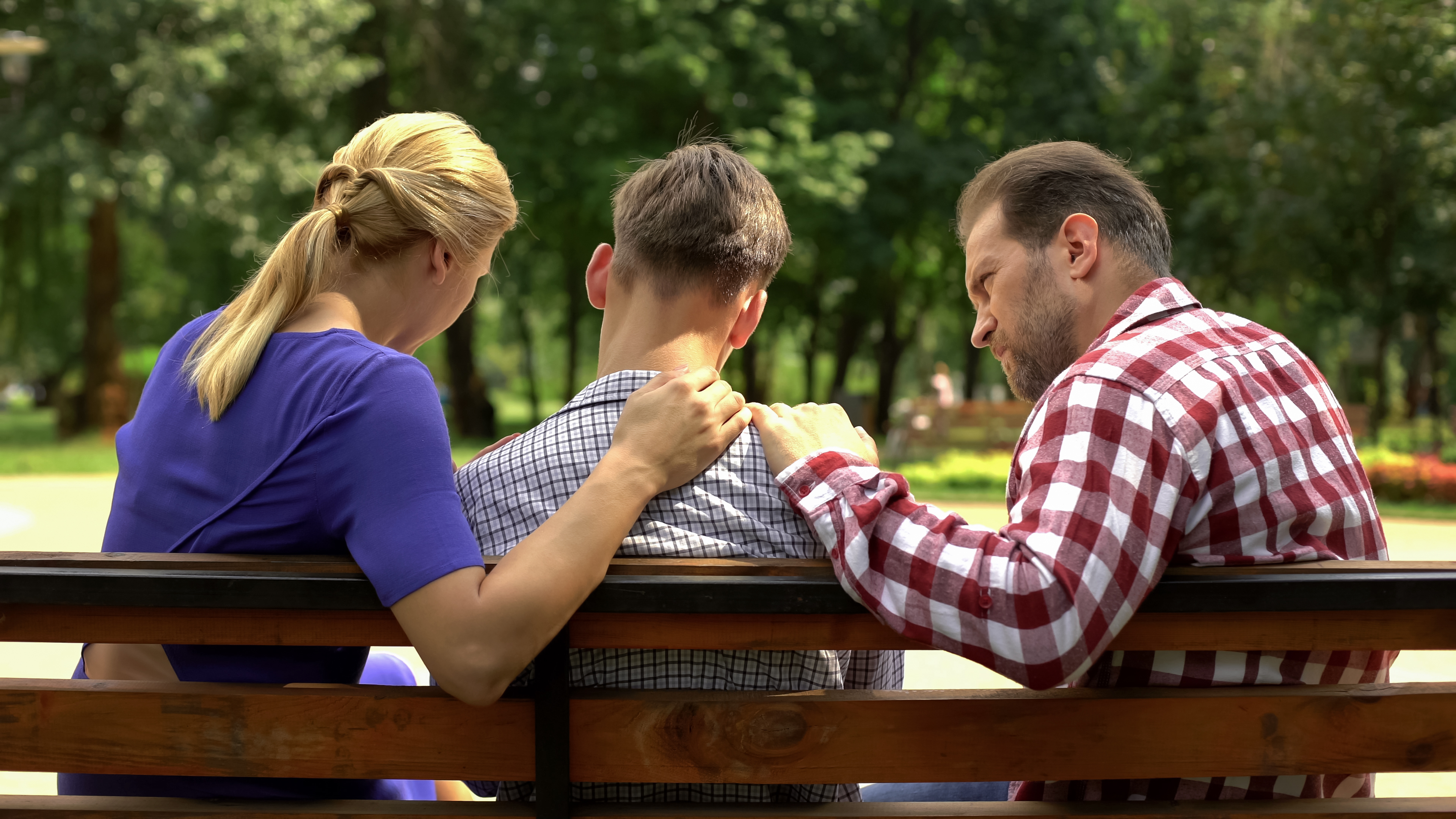 Eltern im Gespräch mit dem Sohn in einem Park | Quelle: Shutterstock
