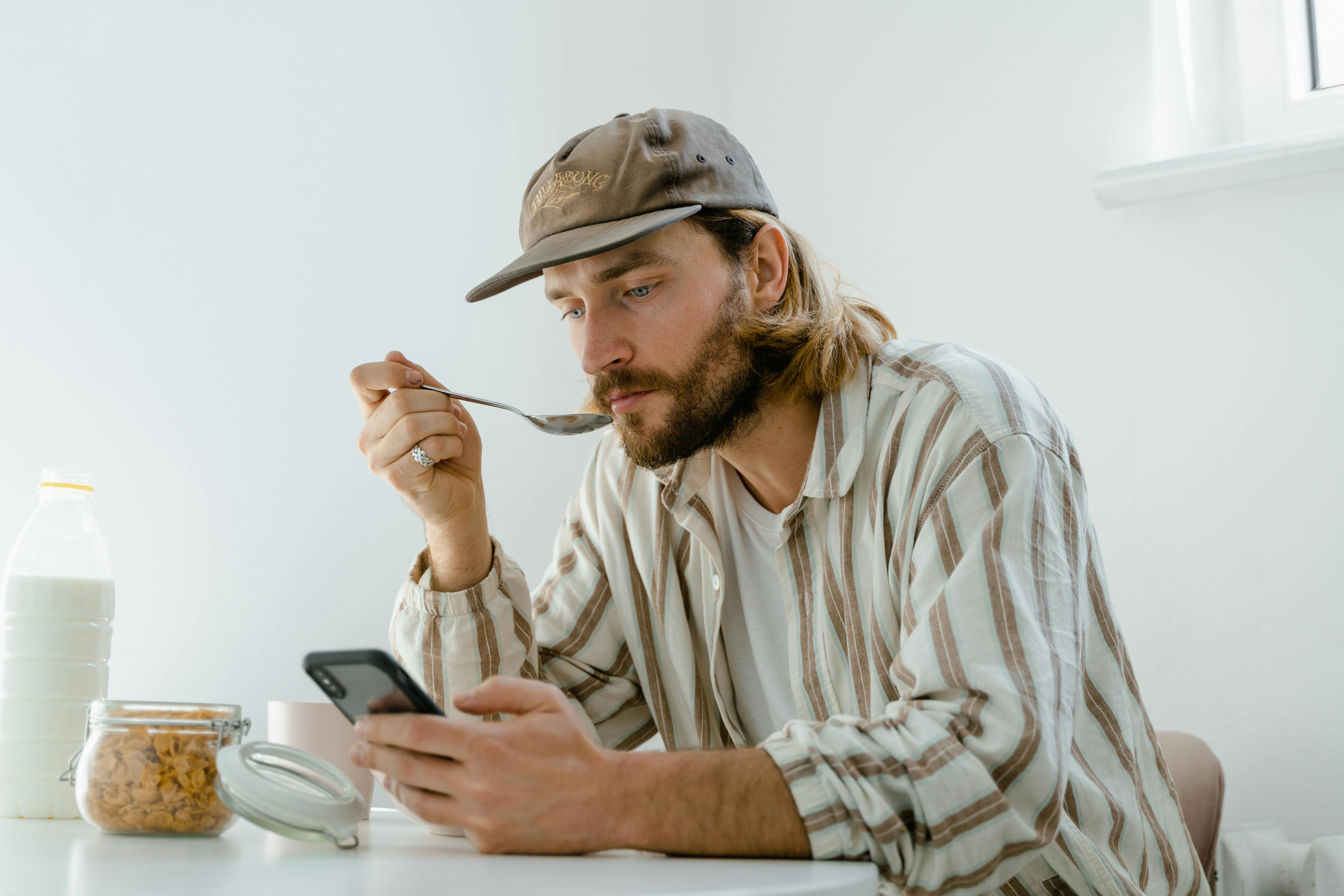 Ein Mann schreibt eine SMS, während er frühstückt | Quelle: Pexels