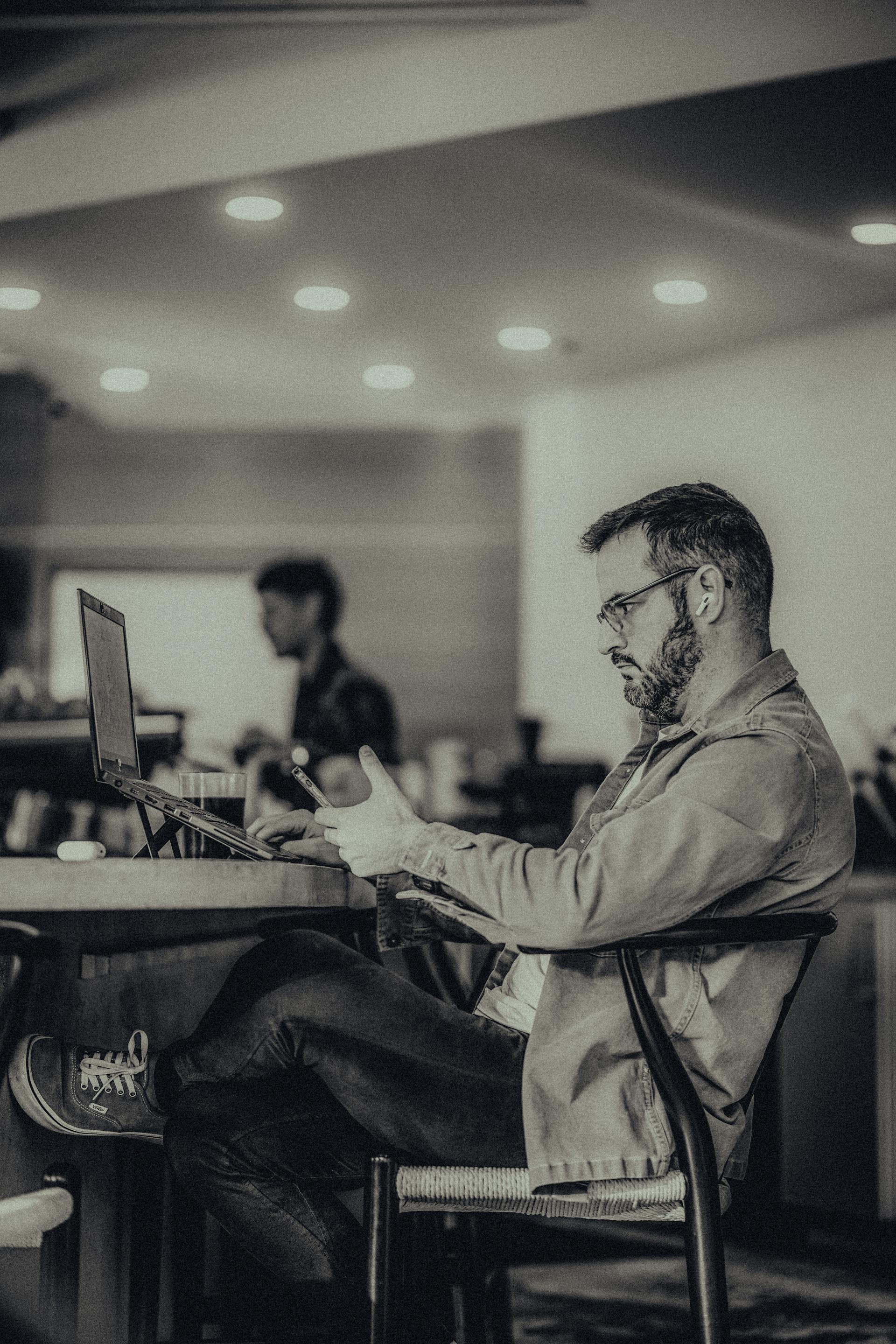 Ein Mann sitzt in einem Büro und benutzt sein Telefon | Quelle: Pexels