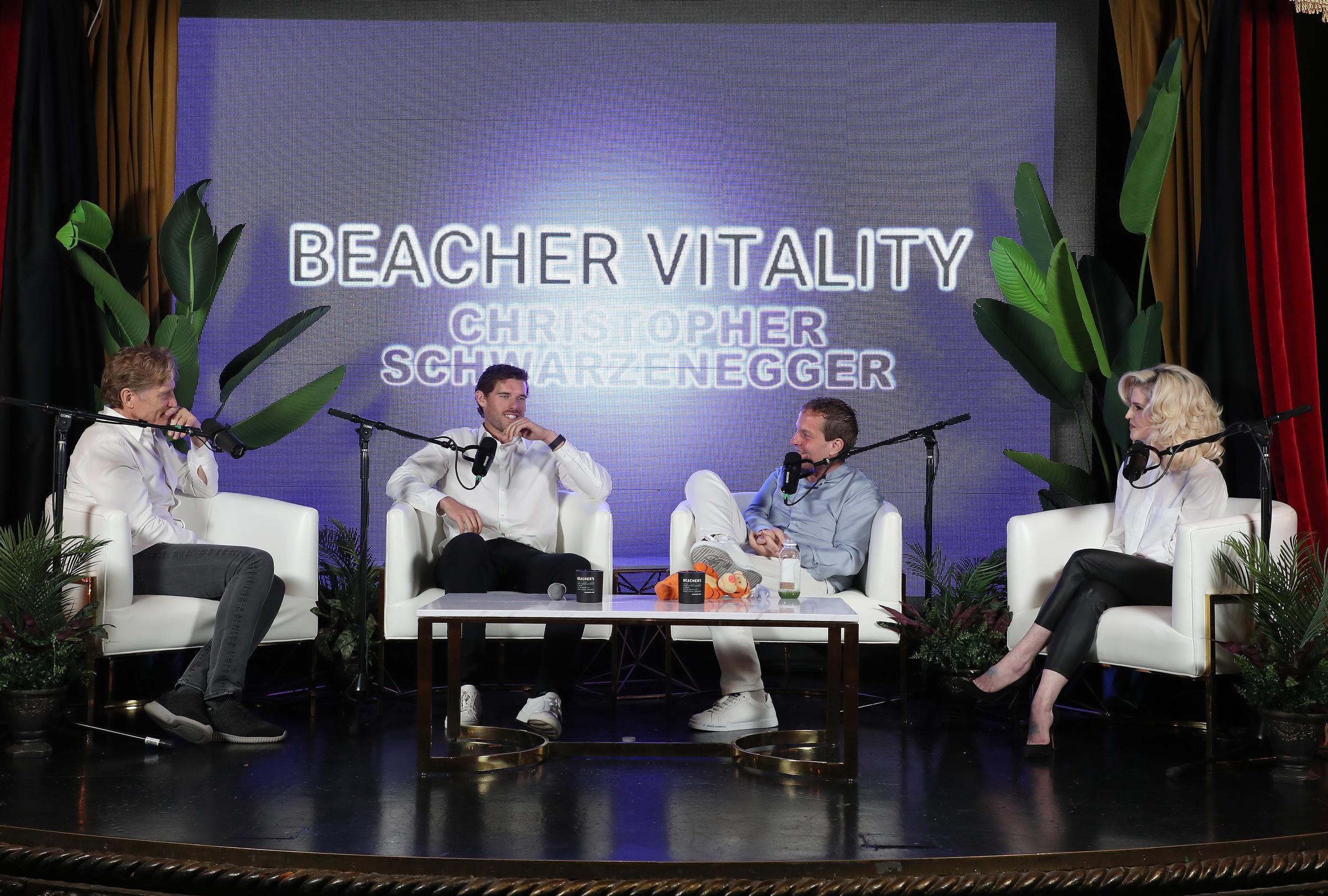 Christopher Schwarzenegger hört aufmerksam zu, während er während einer Podiumsdiskussion mit Jeff Beacher und Dr. Robert Huizenga Gedanken austauscht. Seine gelassene Körpersprache und sein scharfes Auftreten spiegeln die Konzentration und das Selbstvertrauen wider, die er auf seiner Gesundheitsreise gewonnen hat.