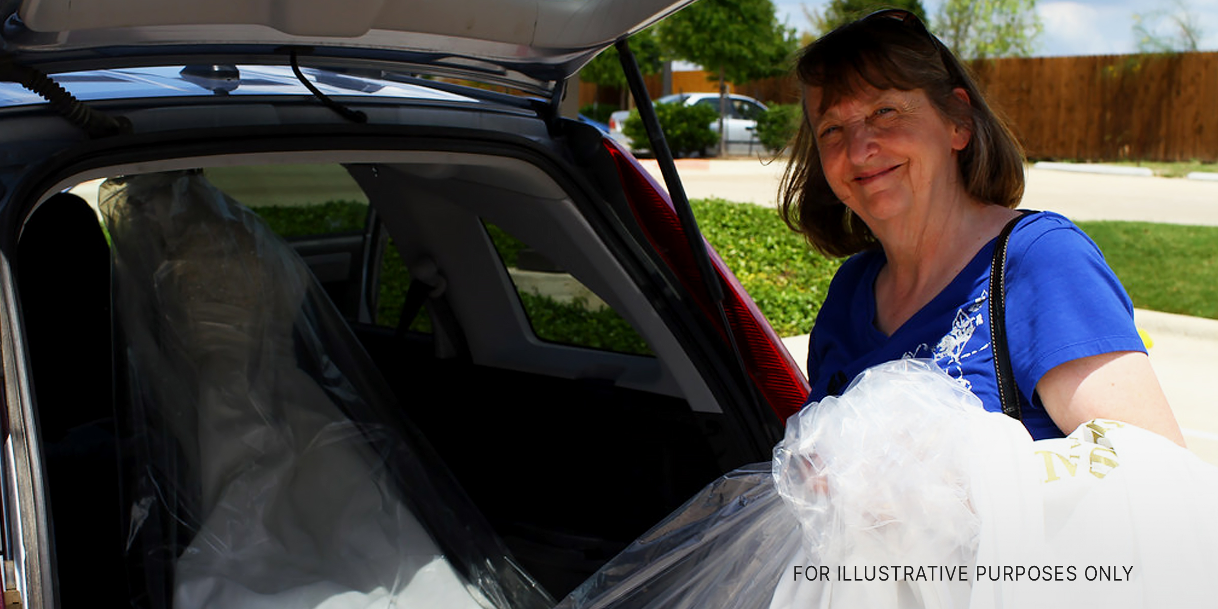 Eine ältere Frau holt ein Brautkleid aus dem Kofferraum ihres Autos | Quelle: Flickr/waitscm/CC BY 2.0