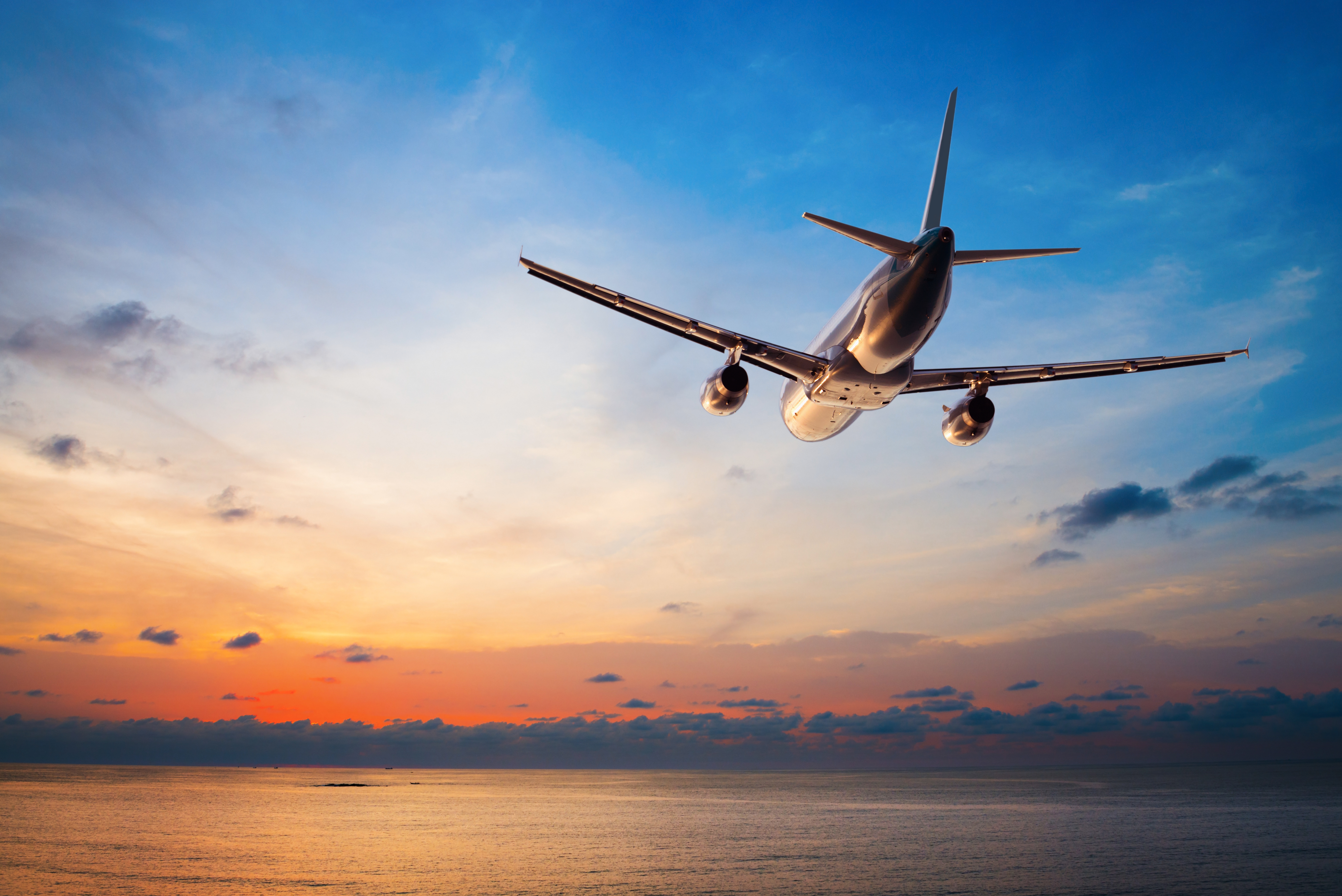 Ein Flugzeug fliegt vor einem Hintergrund mit Sonnenuntergang | Quelle: Shutterstock