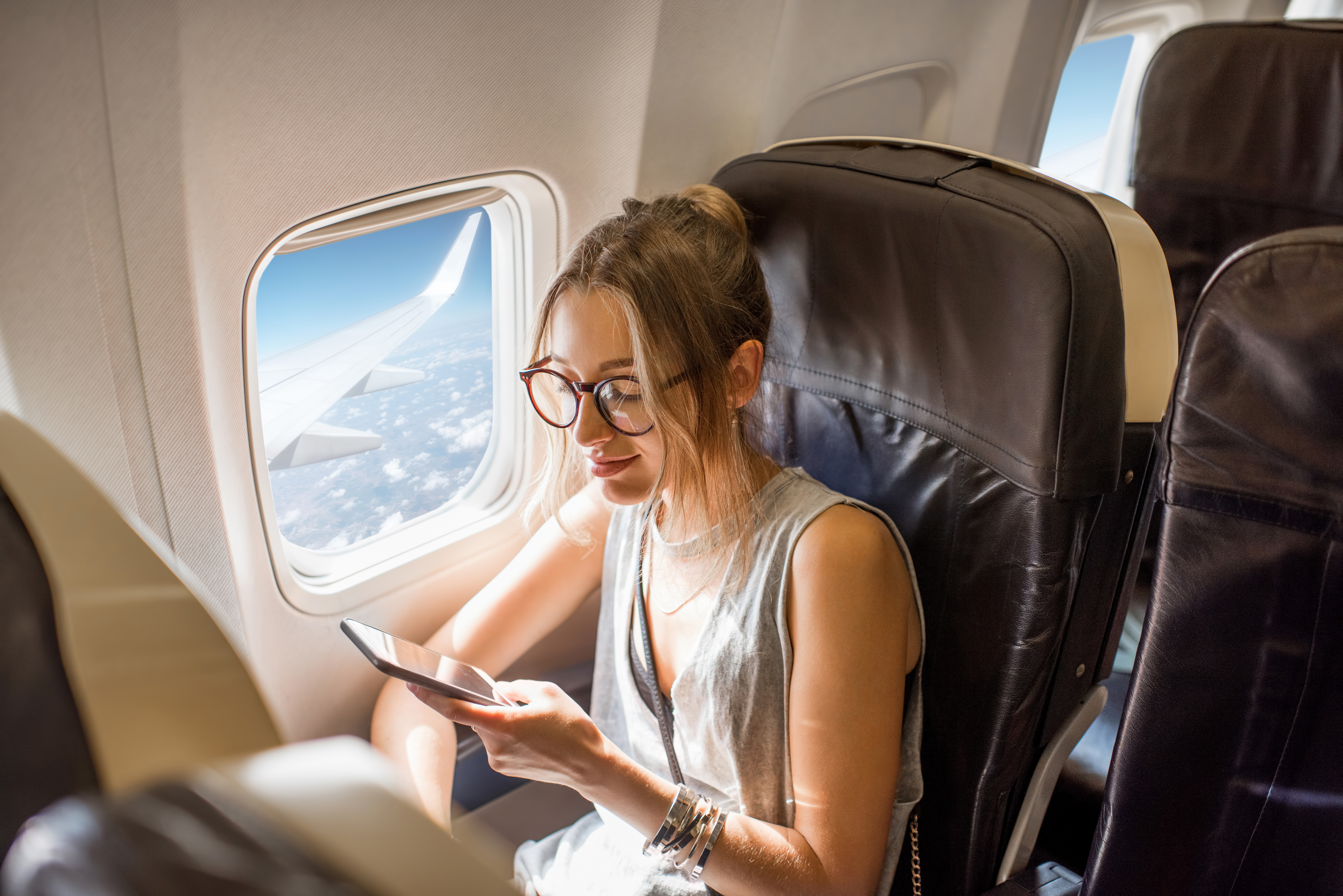 Eine junge Frau hält ihr Telefon während des Fluges | Quelle: Shutterstock
