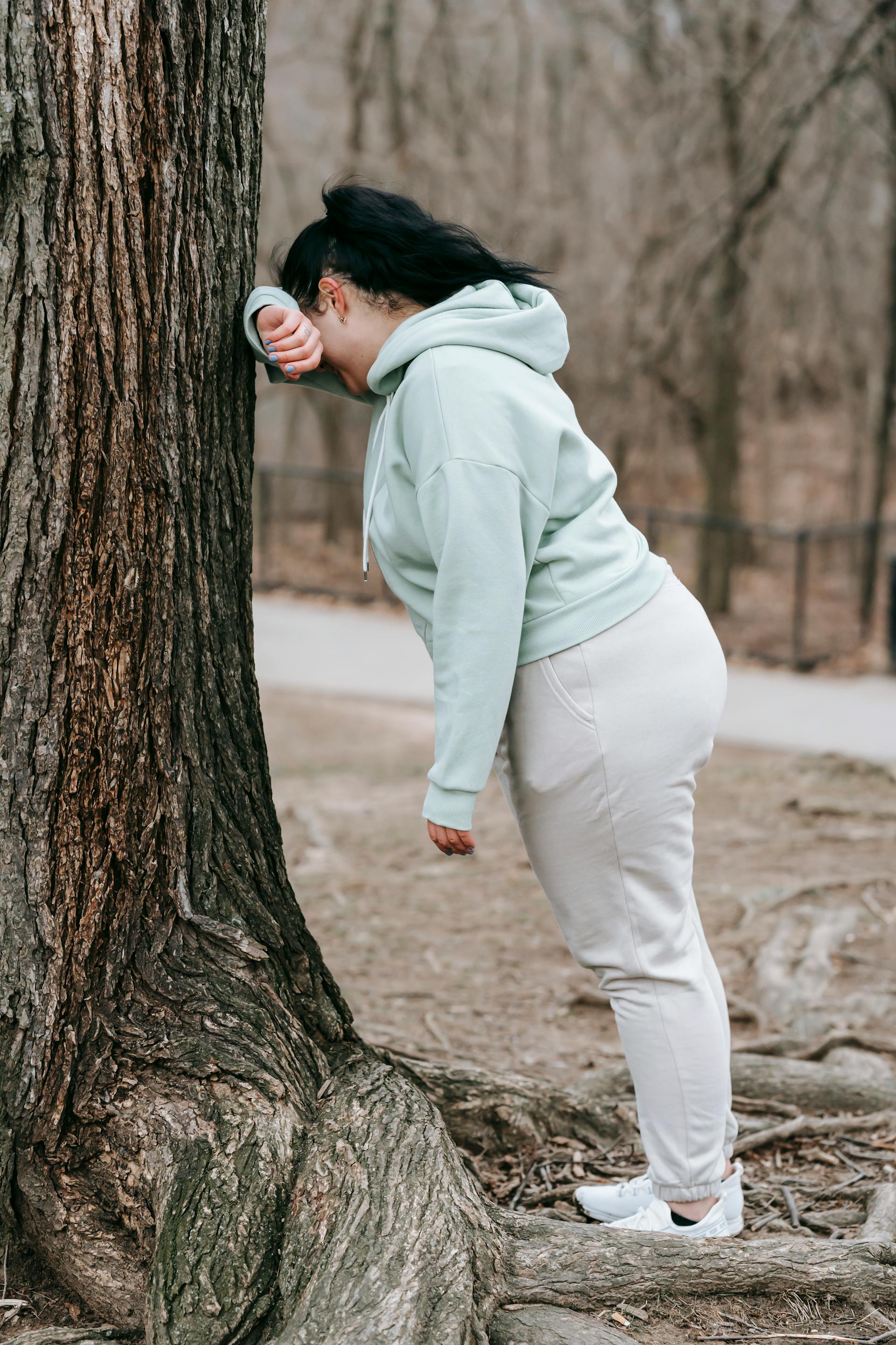 Eine Frau in Activewear lehnt an einem Baum in einem Park | Quelle: Pexels